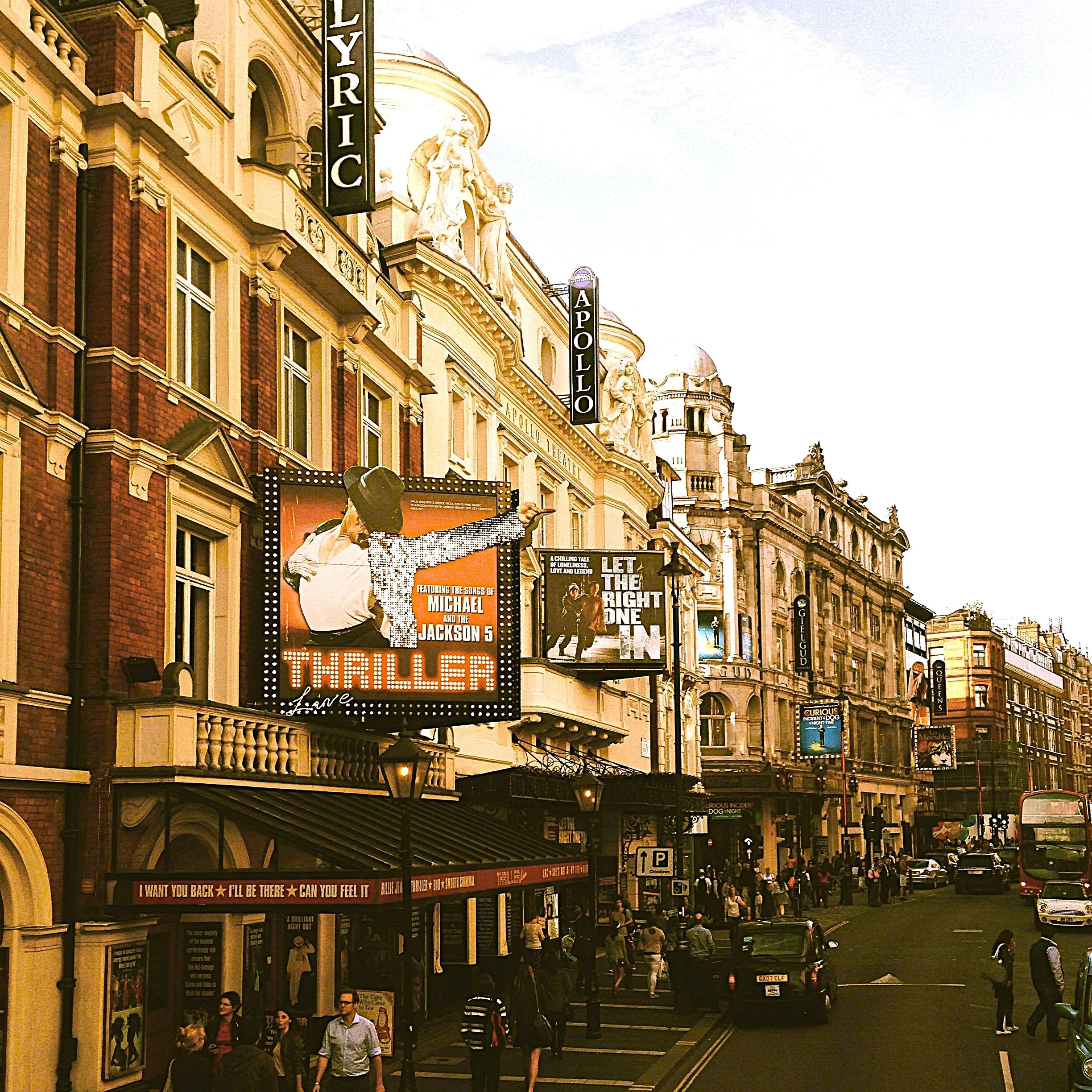 Busy West End street with pub signs and old brick buildings glowing in the evening light, London
