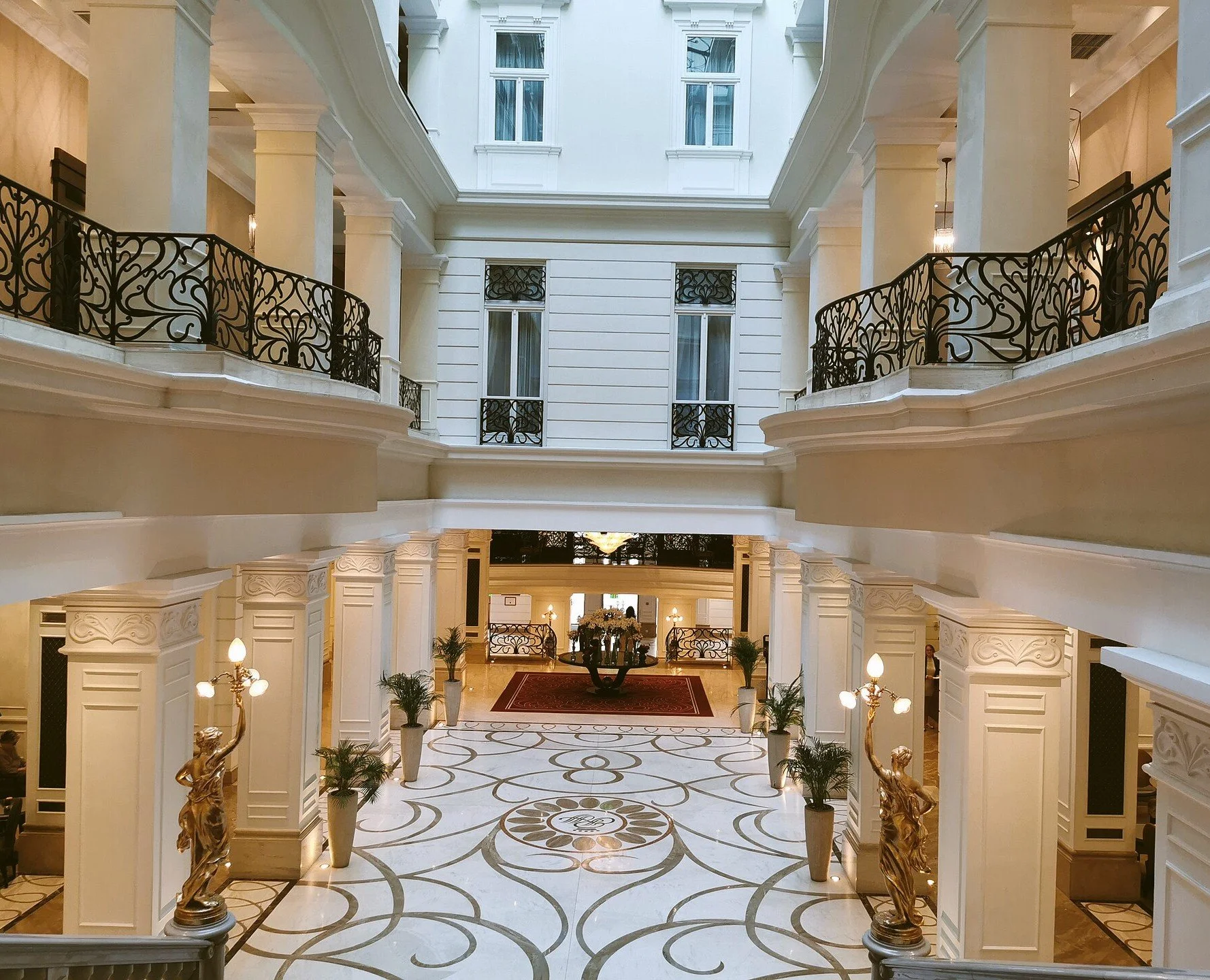 Elegant lobby of the Corinthia hotel with marble floors, white columns and decorative statues, Budapest