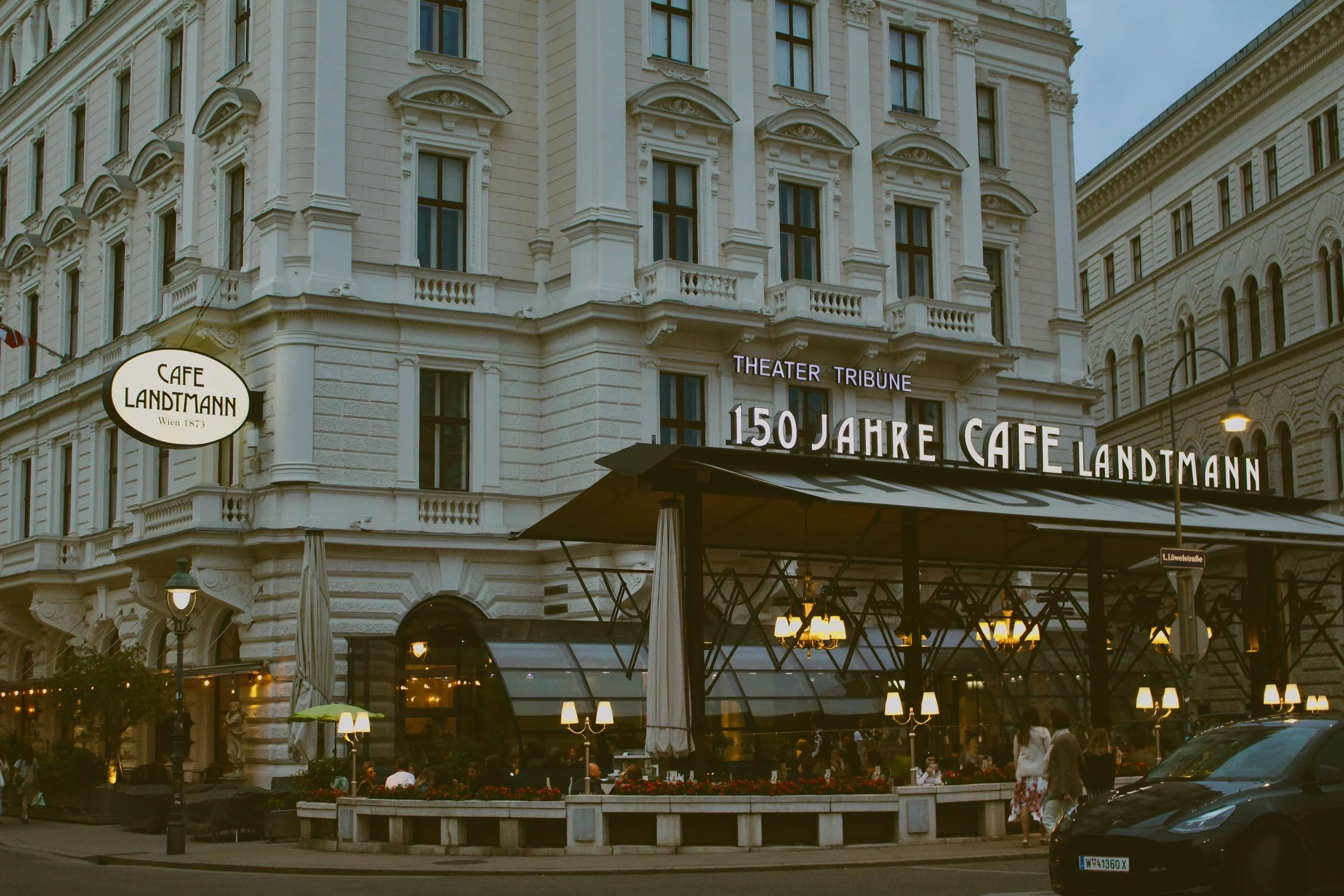 Café Landtmann exterior with its terrace and awning in front of a light stone building, Vienna.