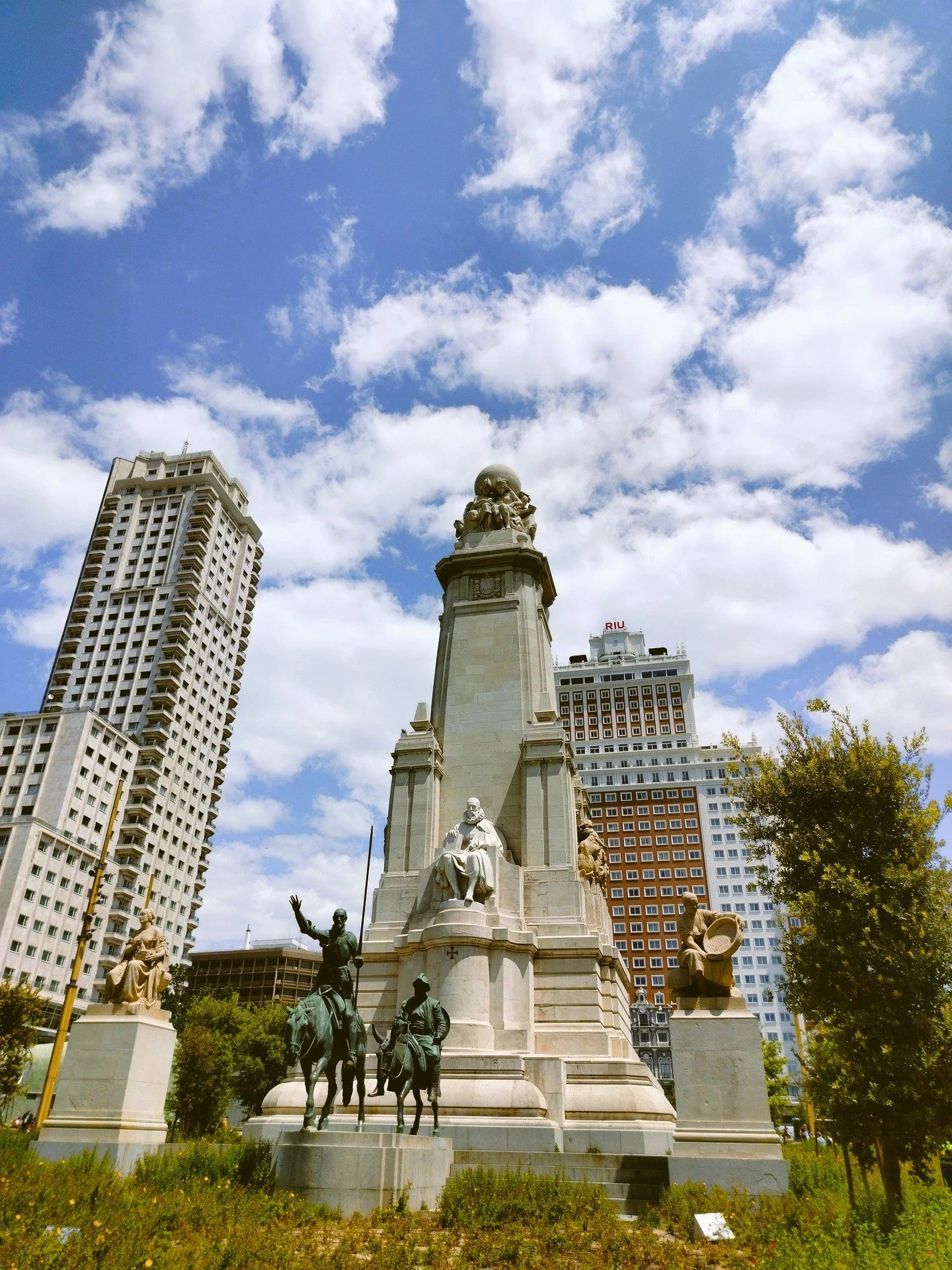 Cervantes Monument with Don Quixote and Sancho Panza statues under a cloudy blue sky, Plaza de España, Madrid