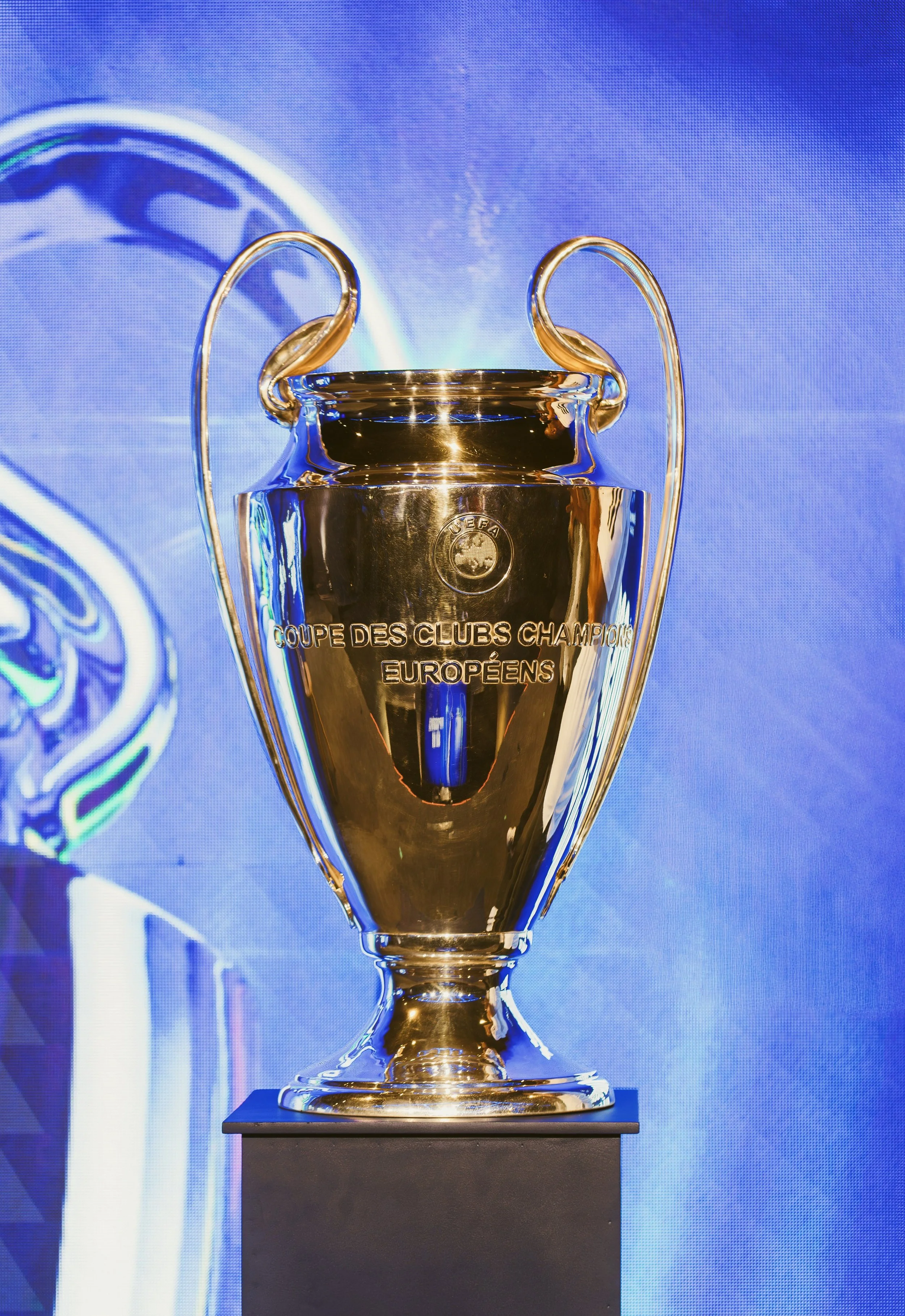 Golden Champions League trophy displayed on a pedestal against a blue background