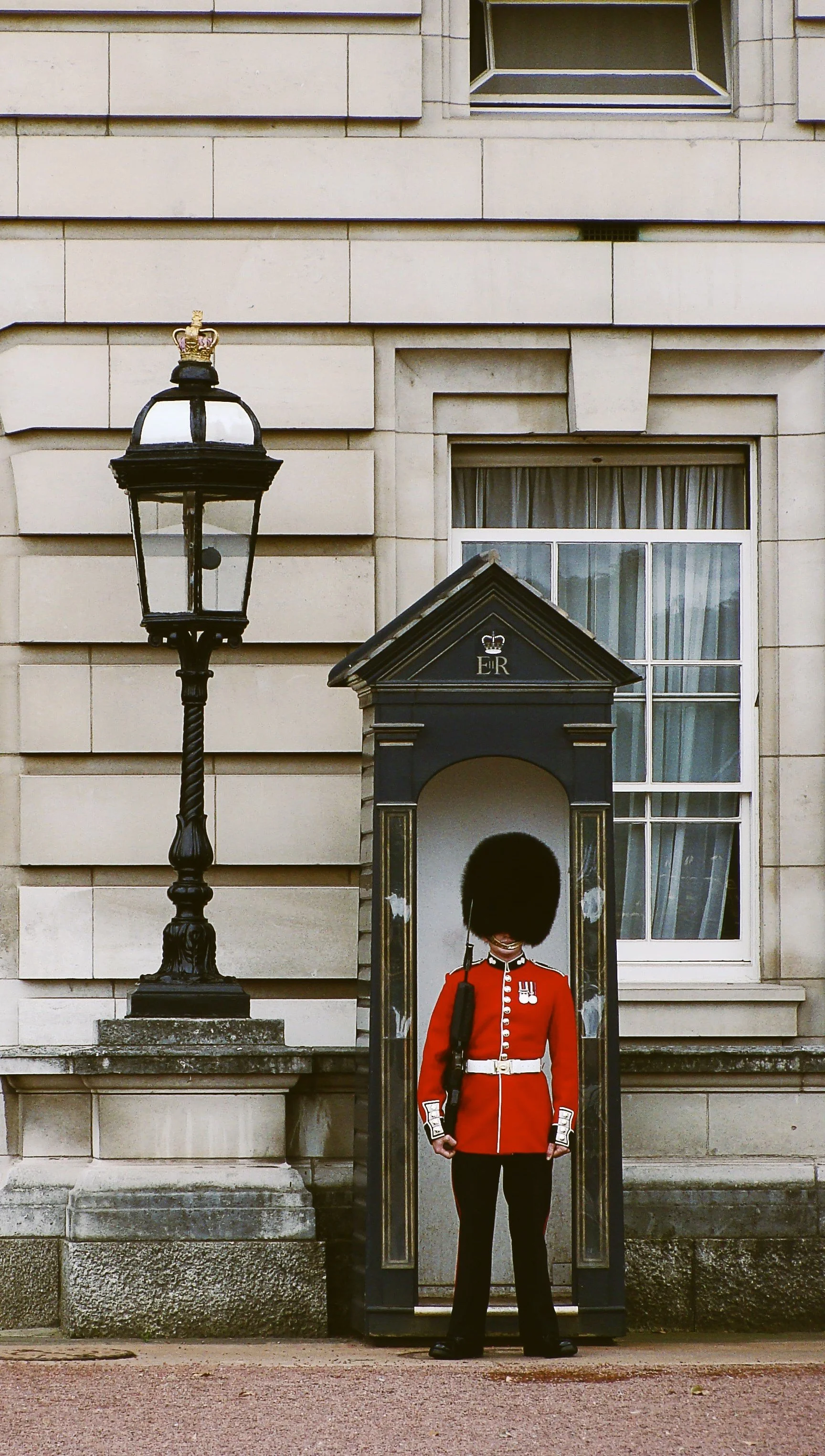 Royal guard standing beside a lamppost outside a historic building, London