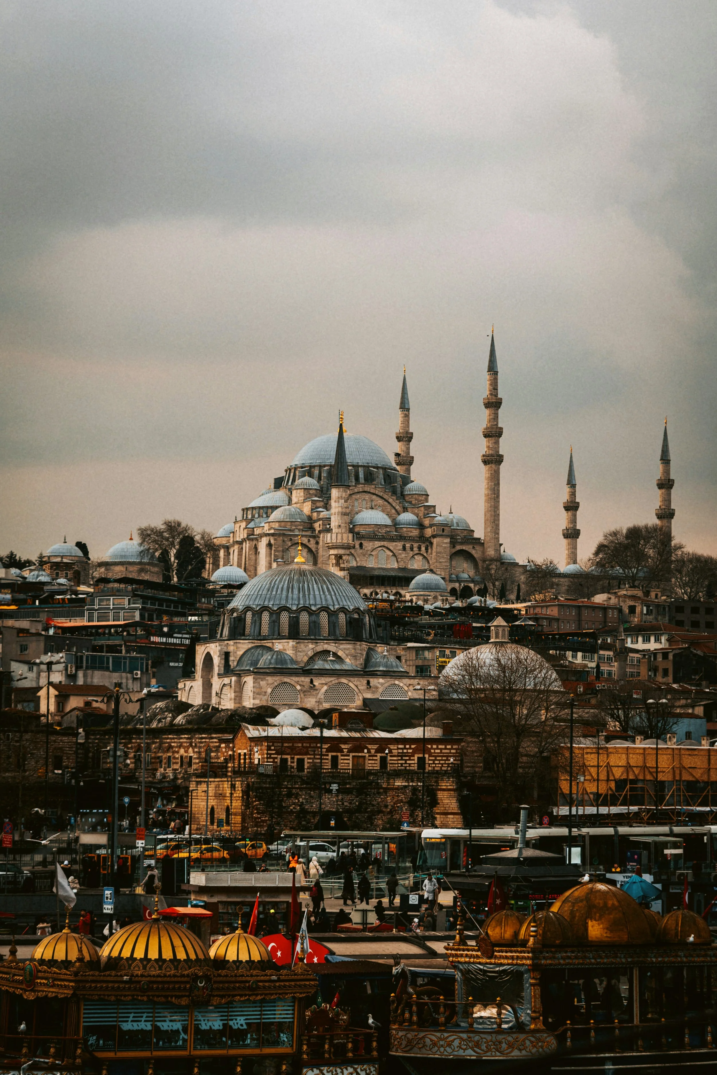 Skyline of Istanbul with a large domed mosque and minarets above the rooftops and ferries in the foreground.