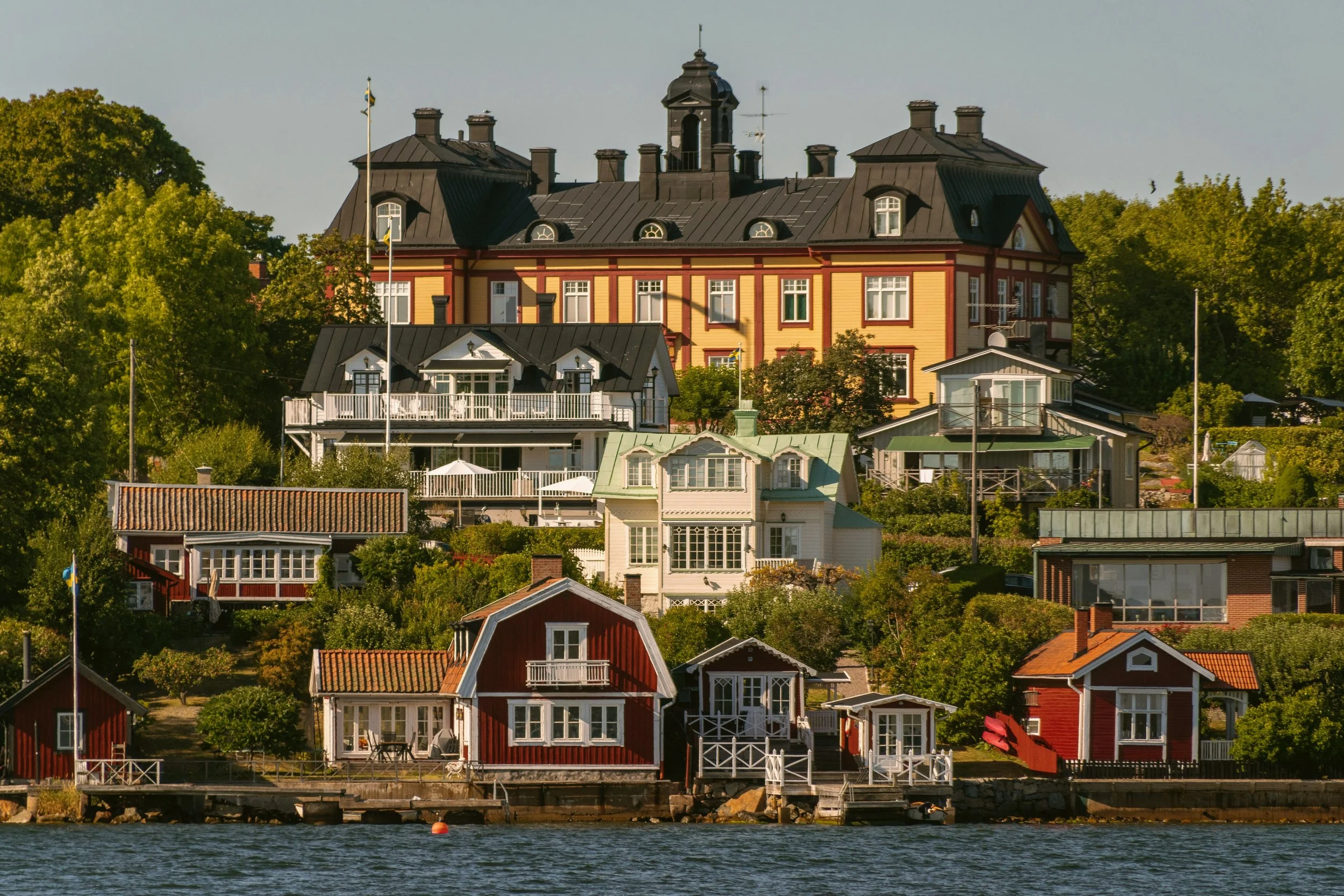 Grand mansion above red wooden boathouses on Vaxholm island, Stockholm archipelago