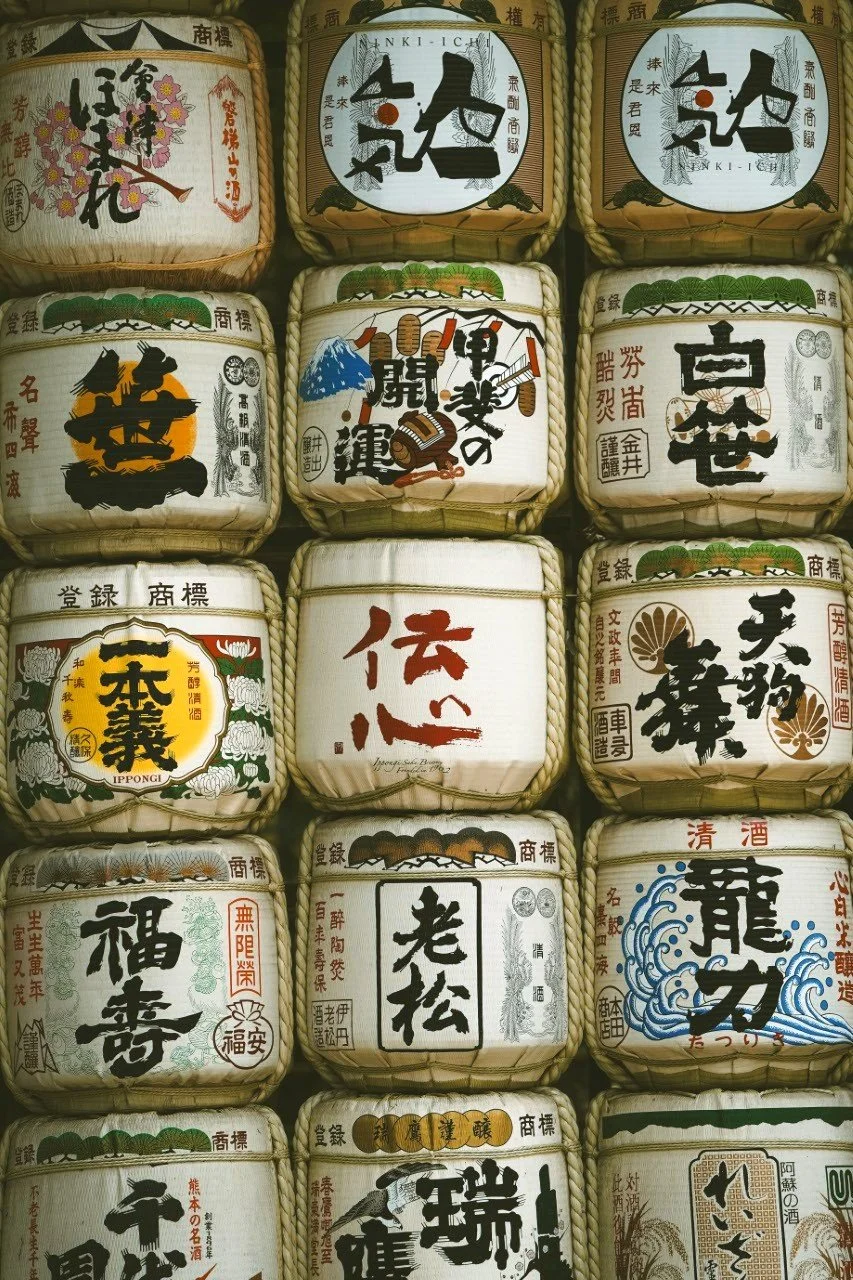 Japanese sake barrels with traditional calligraphy and artwork in a grid pattern