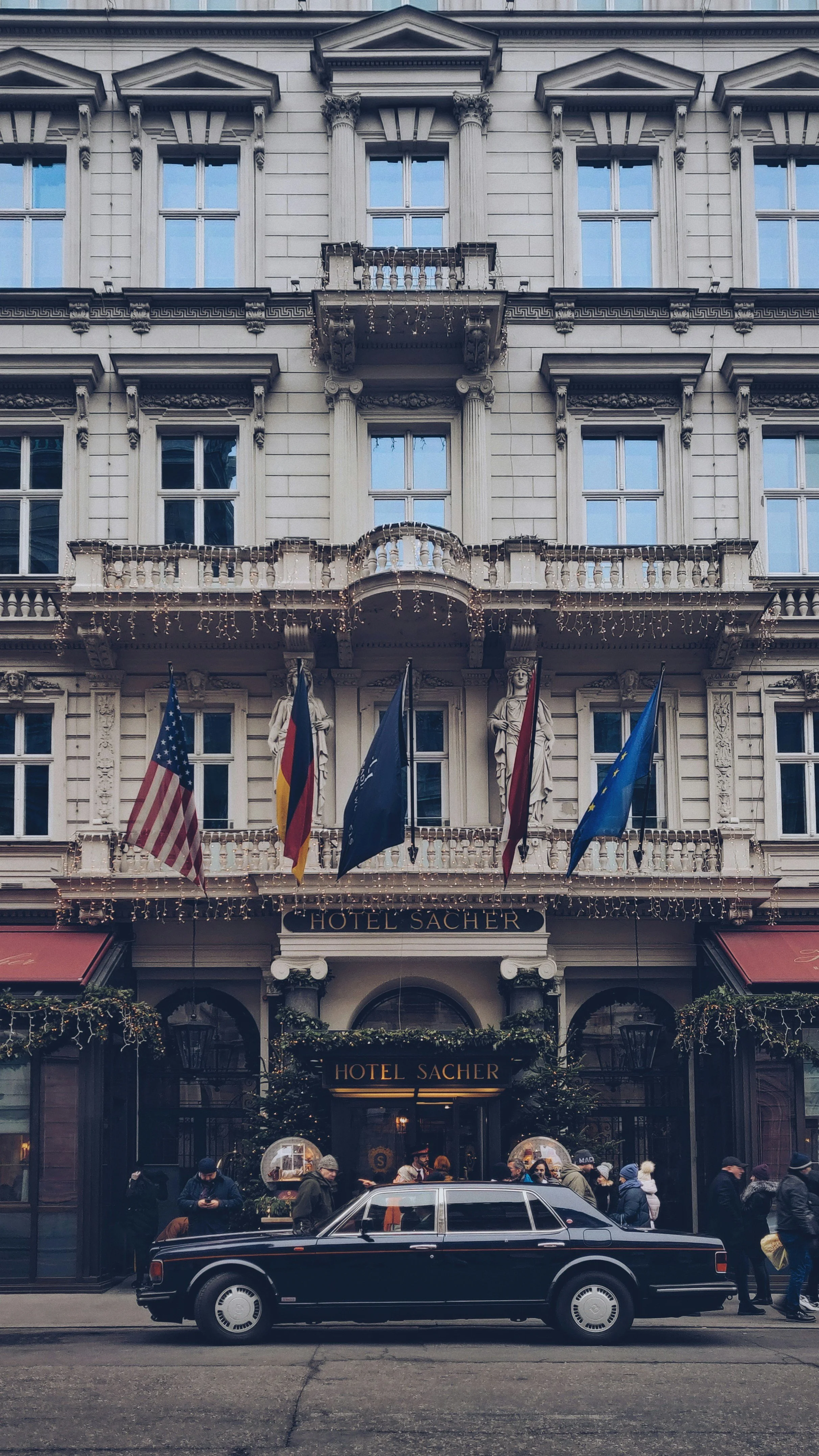 Ornate blue facade of Hotel Sacher with a car parked outside, Vienna