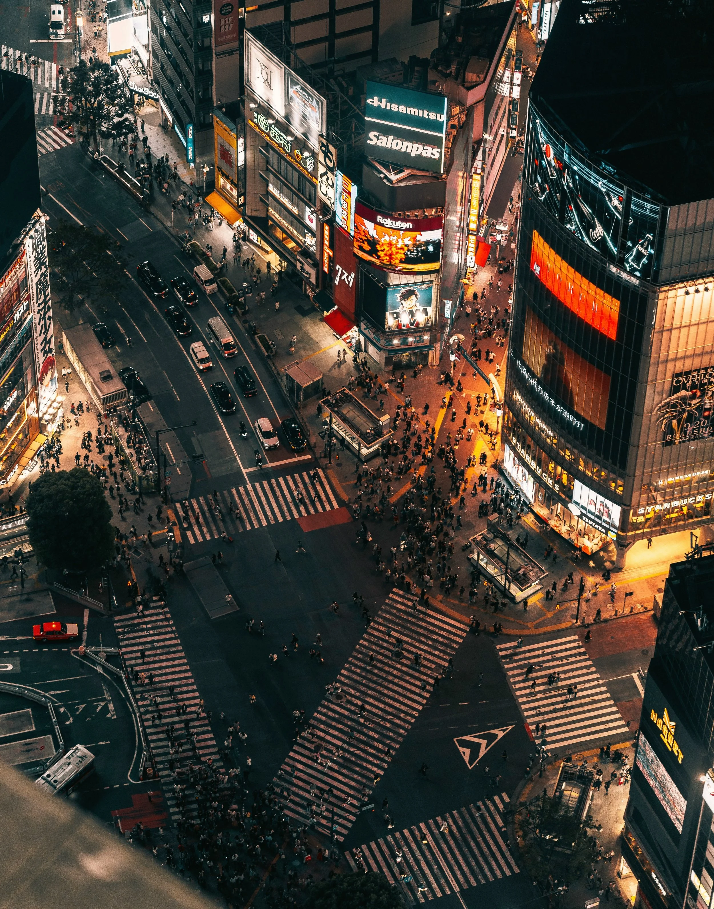 Aerial view of a busy scramble crossing lit up at night with crowds and neon signs, Shibuya, Tokyo.