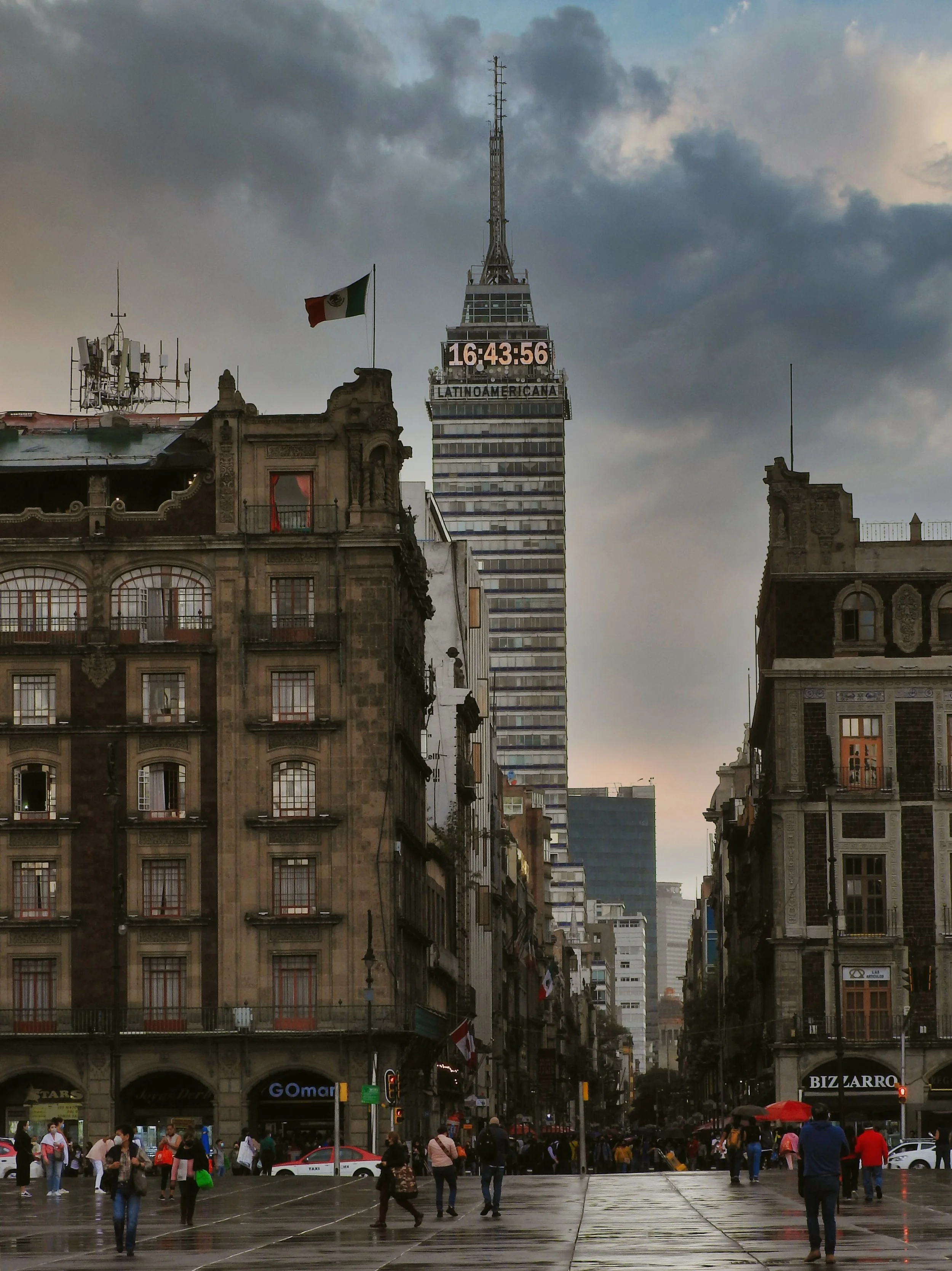 Torre Latinoamericana rising between historic buildings on a cloudy day, Mexico City.