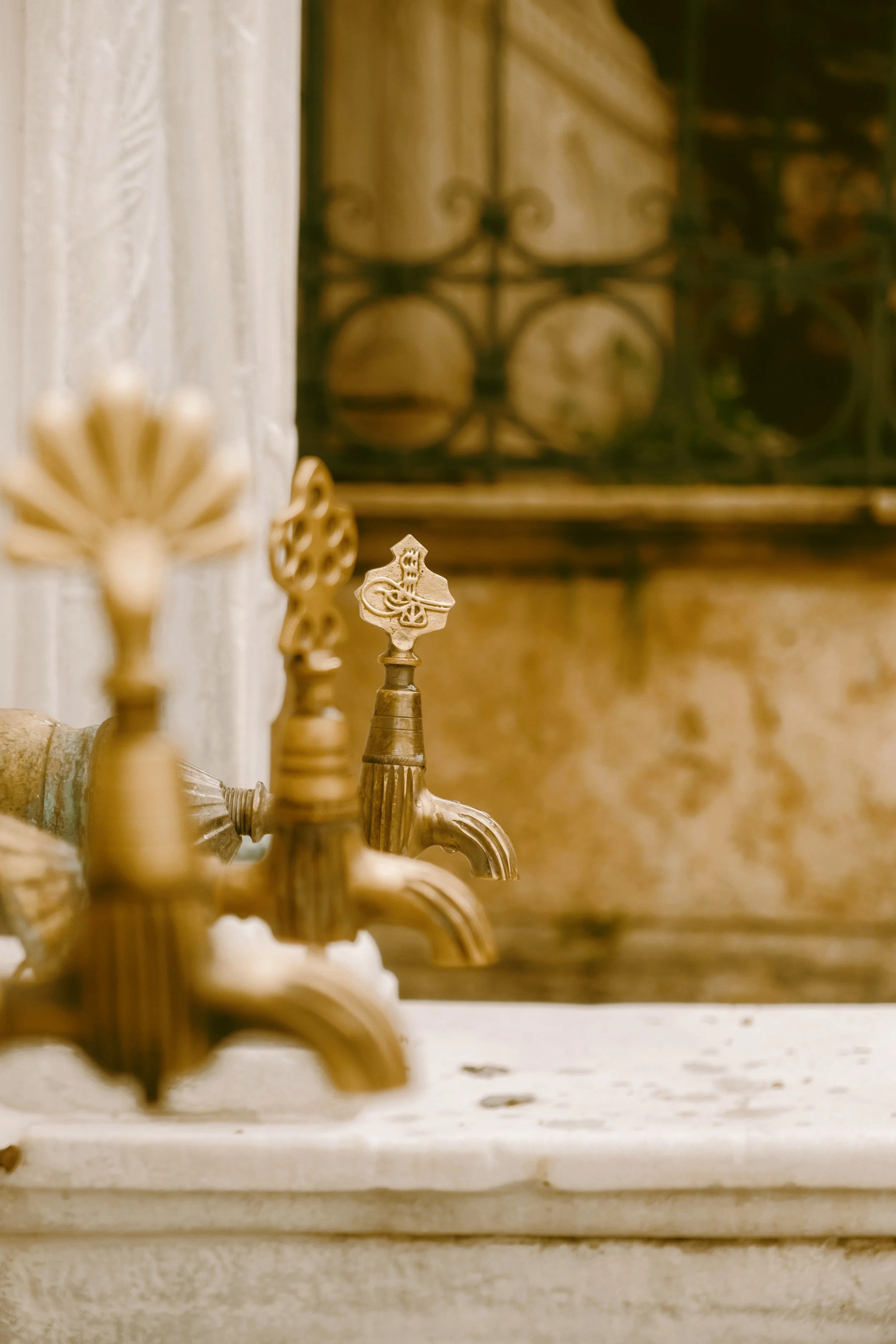 Golden faucet on a marble basin with warm light in a traditional hamam, Istanbul.