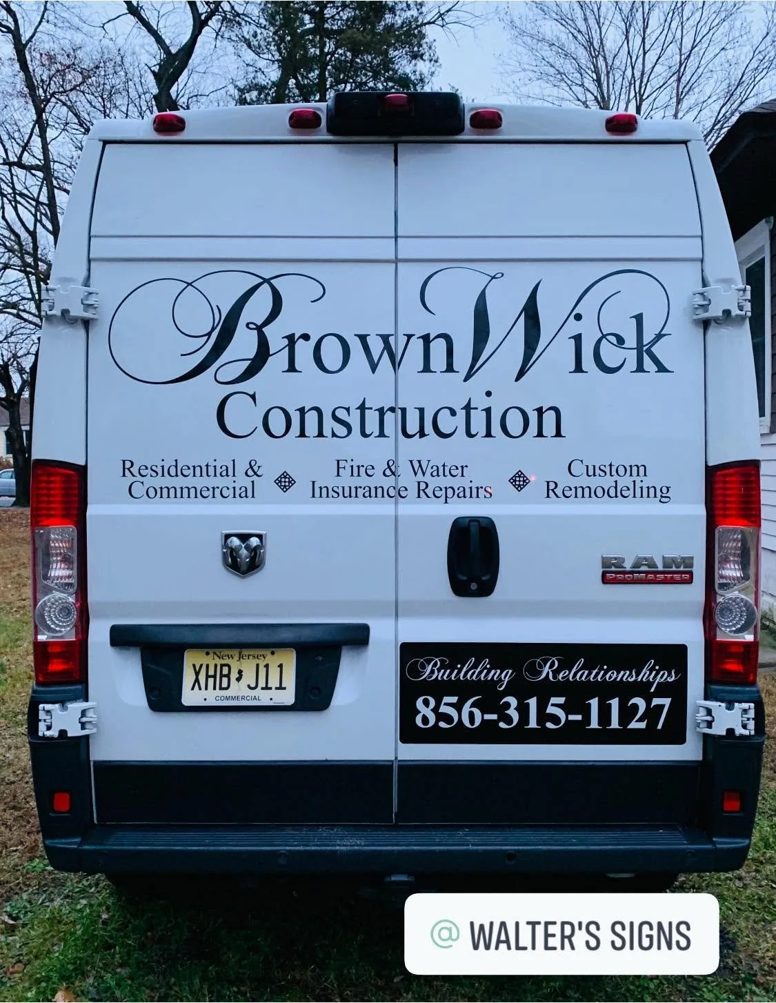 Rear view of a white construction company's van with the company name Brown Wick Construction written in large decorative font. The van lists services including residential and commercial work, fire and water insurance repairs, and custom remodeling. Contact number 856-315-1127 is prominently displayed. The license plate reads XHB J11 and the quote 'Building Relationships' is on a black background. The logo and branding are clear and visible.