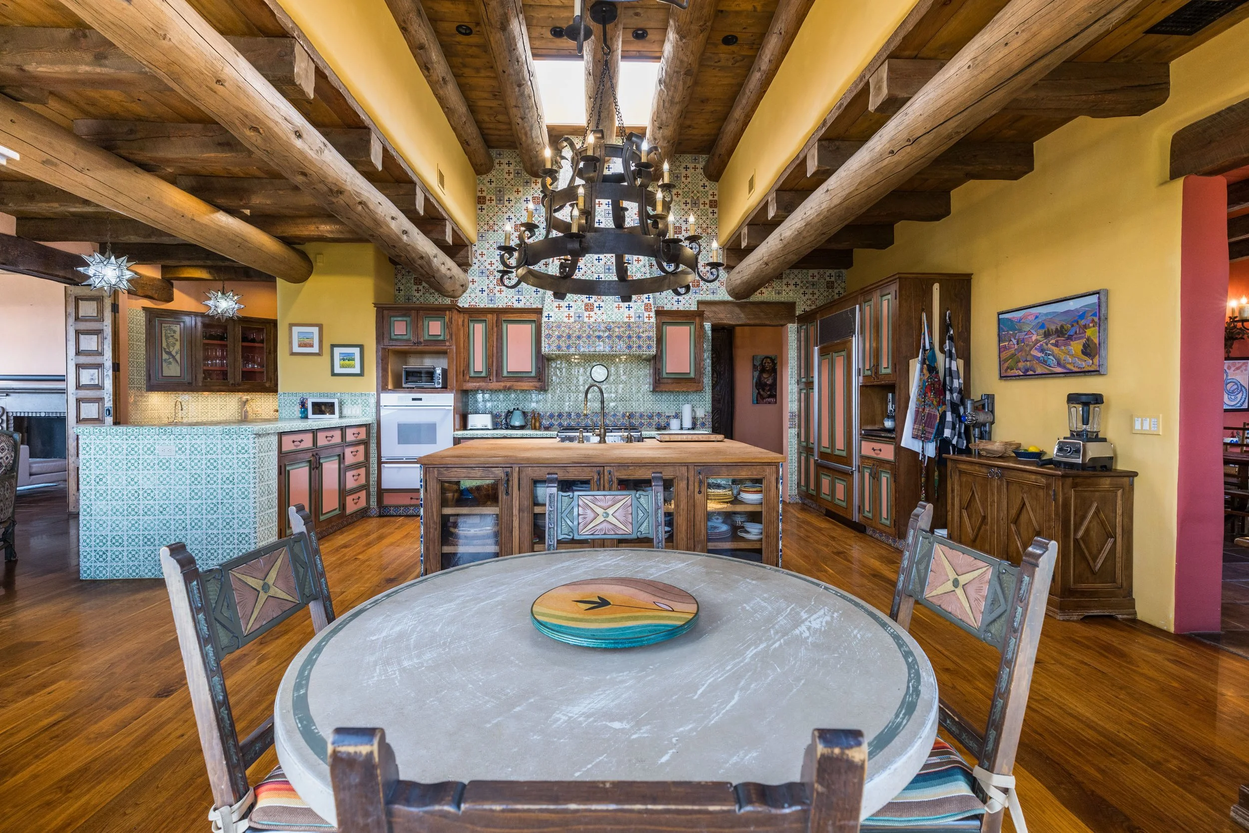 Hand-painted cabinetry, Talavera tile backsplash, and viga ceiling in the kitchen at SENDERO luxury compound Taos NM