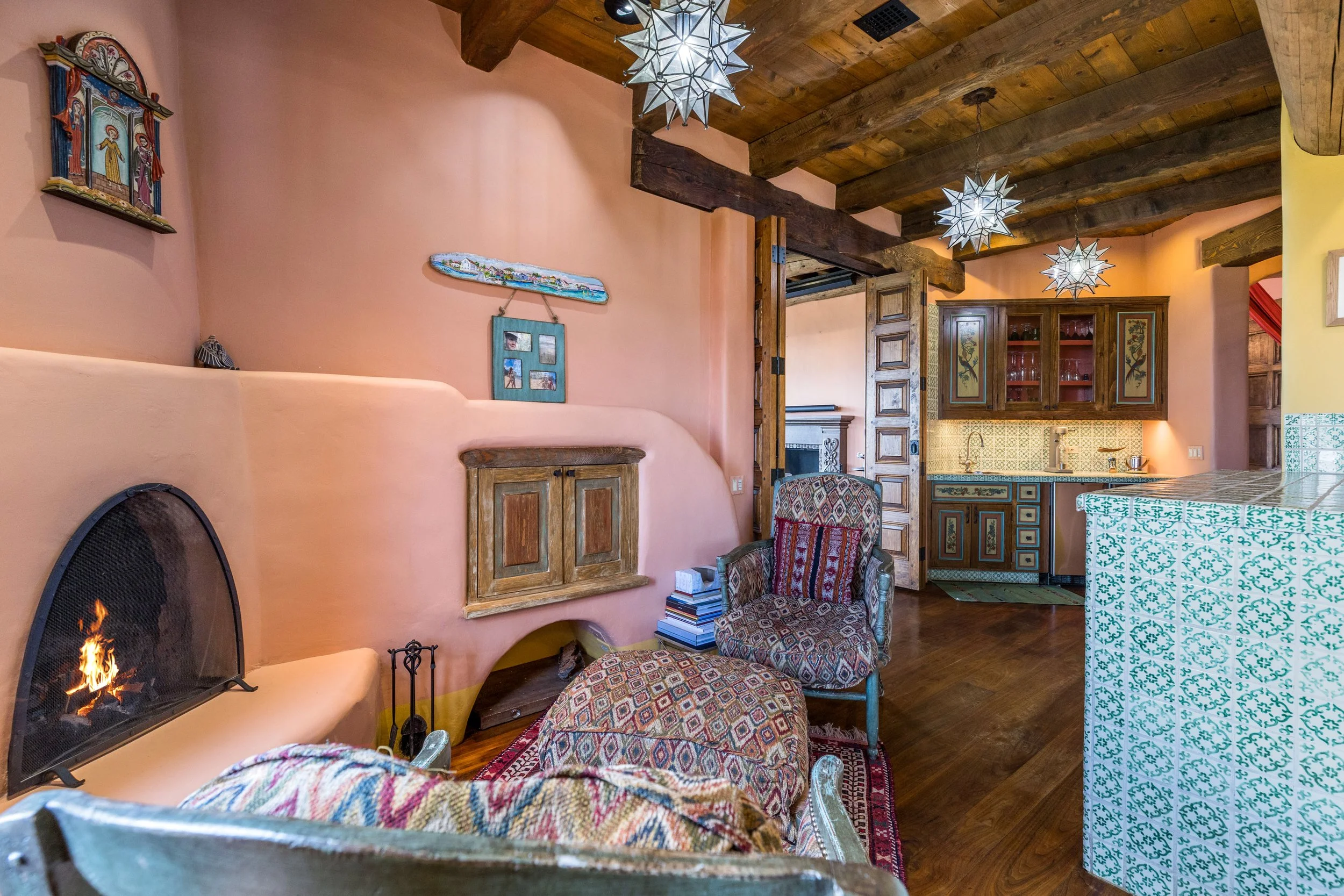 Adobe living room with kiva fireplace, star pendant lights, and viga ceiling at SENDERO luxury compound Taos New Mexico