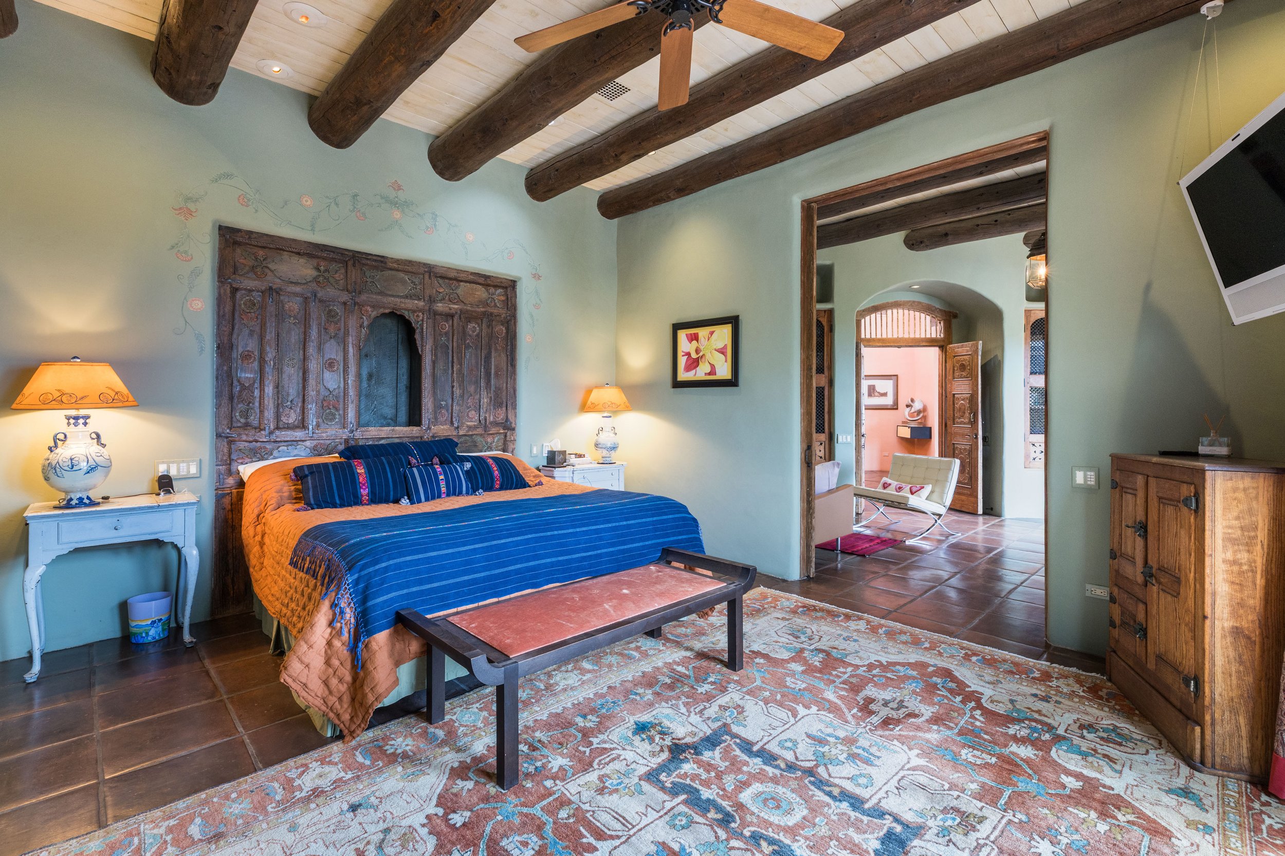 Master bedroom with exposed viga ceiling, Saltillo tile floors, and Southwestern textiles at SENDERO luxury estate Taos NM