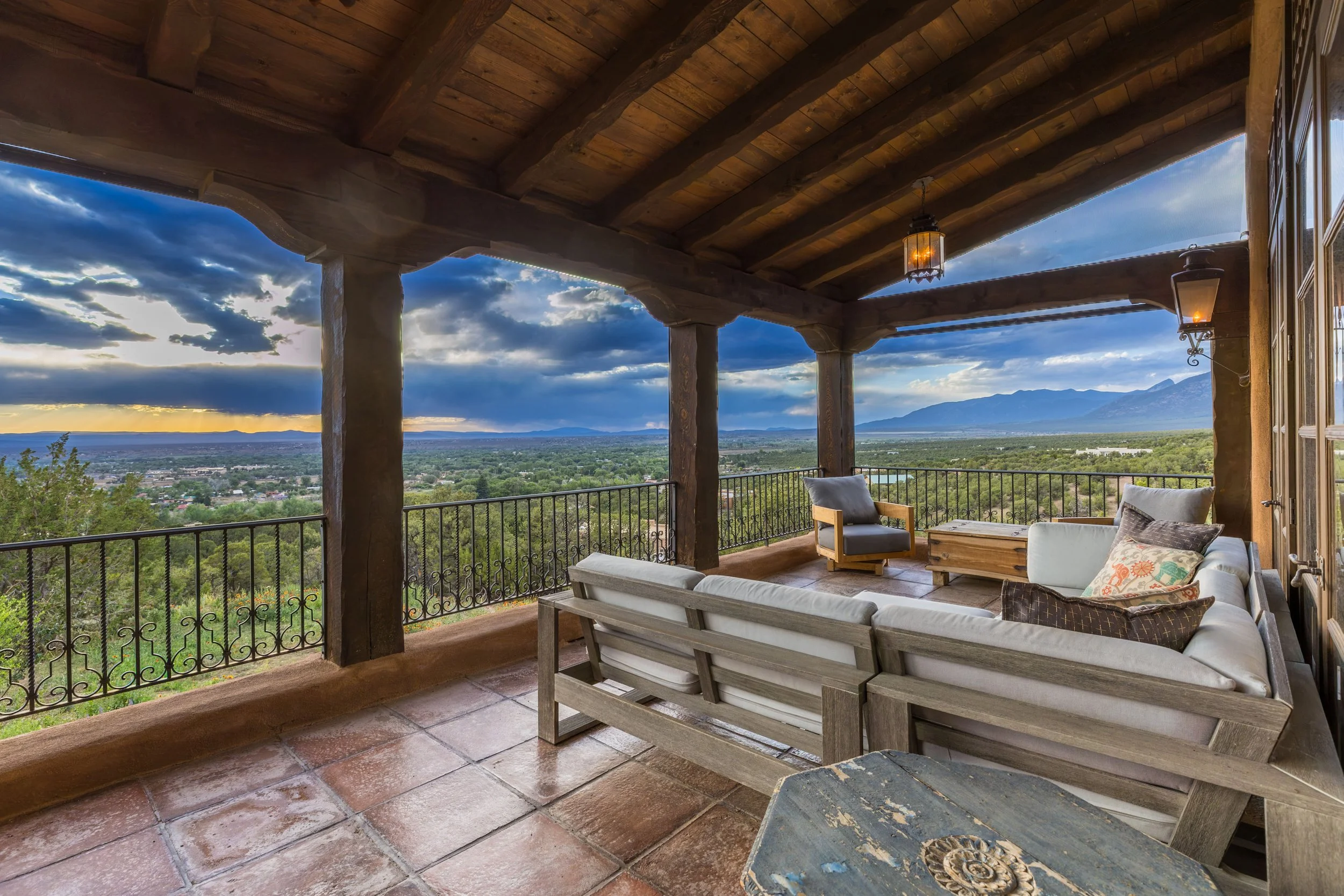 Covered portal with wrought iron railing and panoramic Taos Mountain views at sunset — SENDERO luxury estate Northern New Mexico