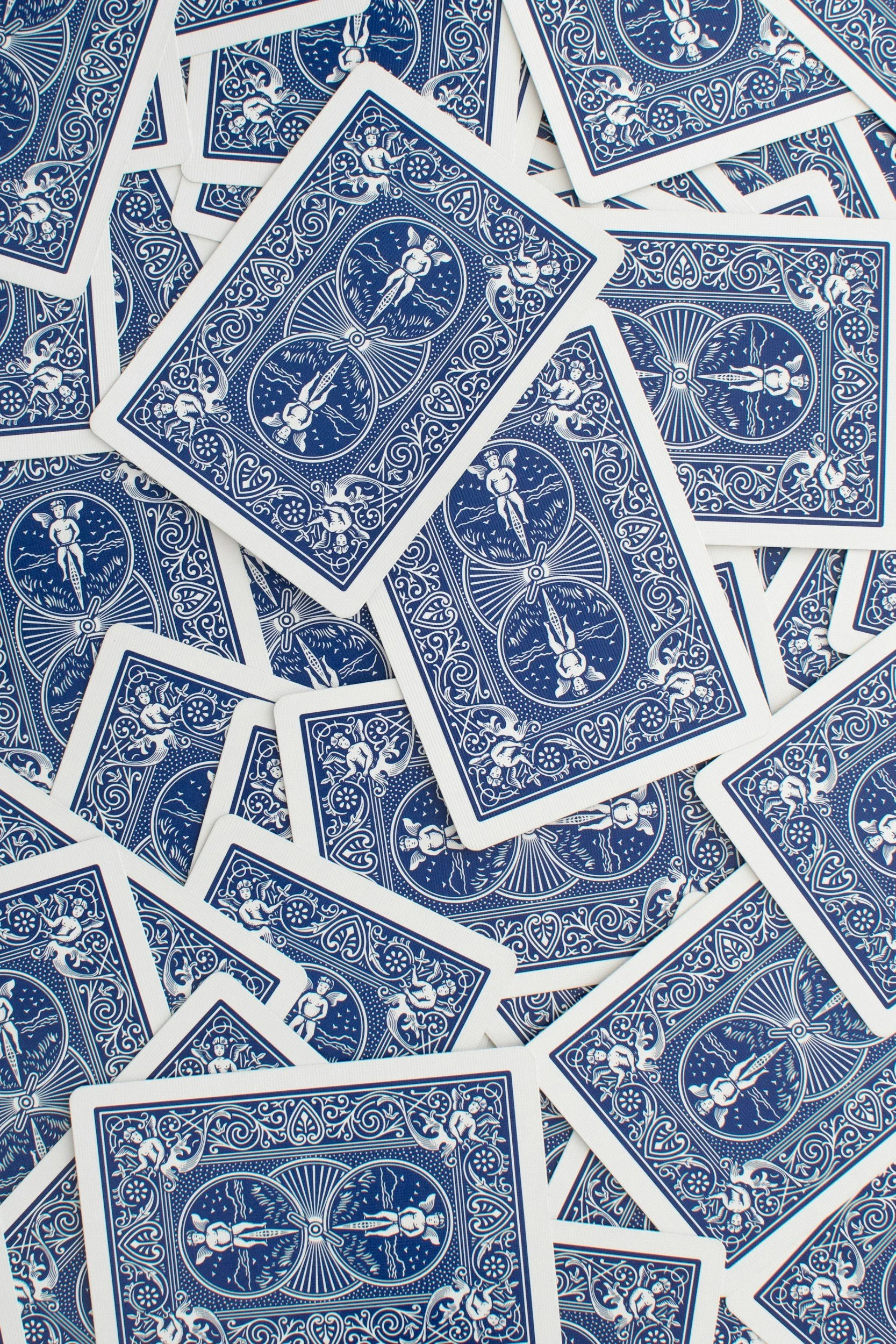A pile of blue and white playing cards with detailed back design, partially overlapping each other.