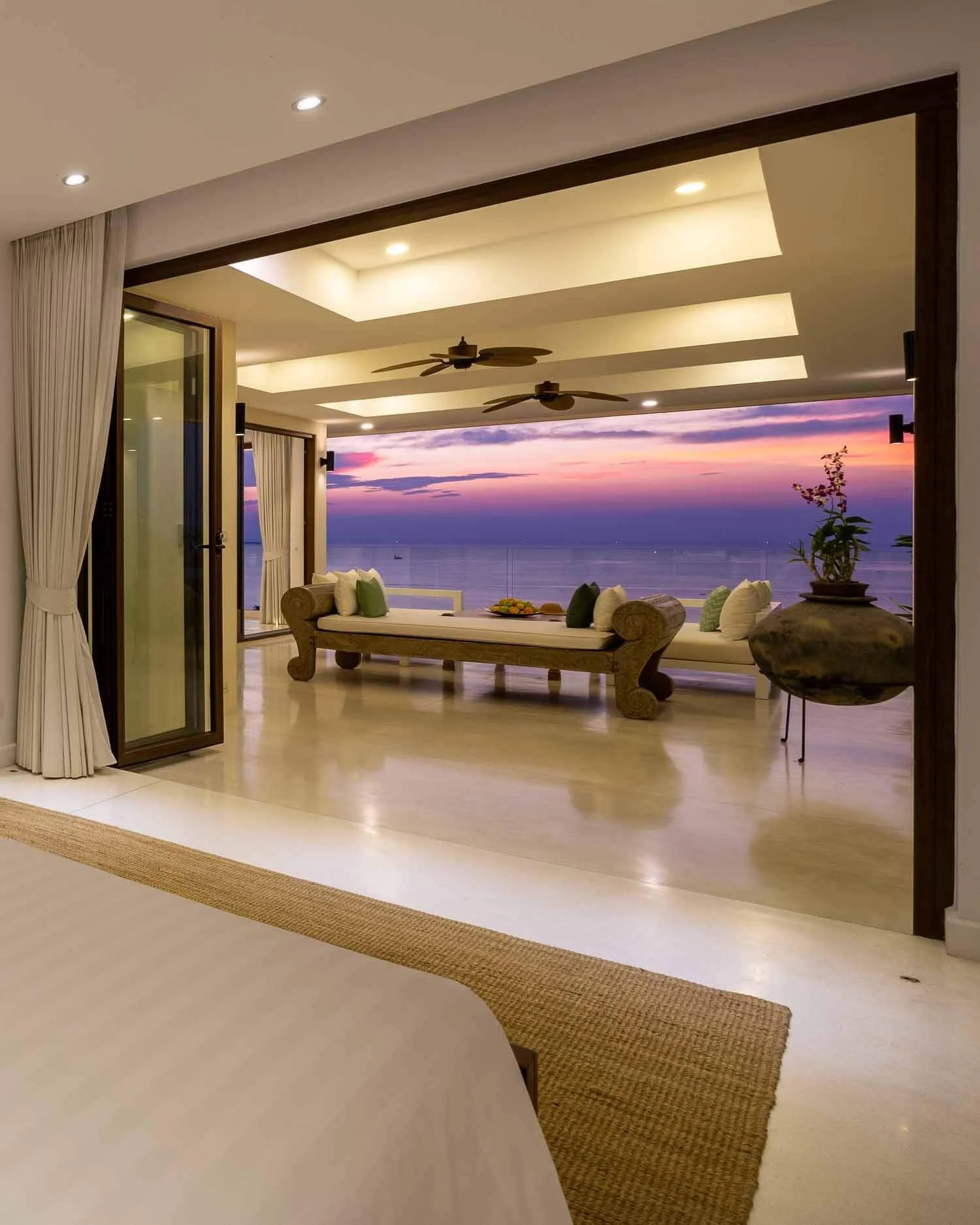 Twin beds with teal pillows and a direct view leading out to the open-air terrace and coastal landscape at Saensook villa