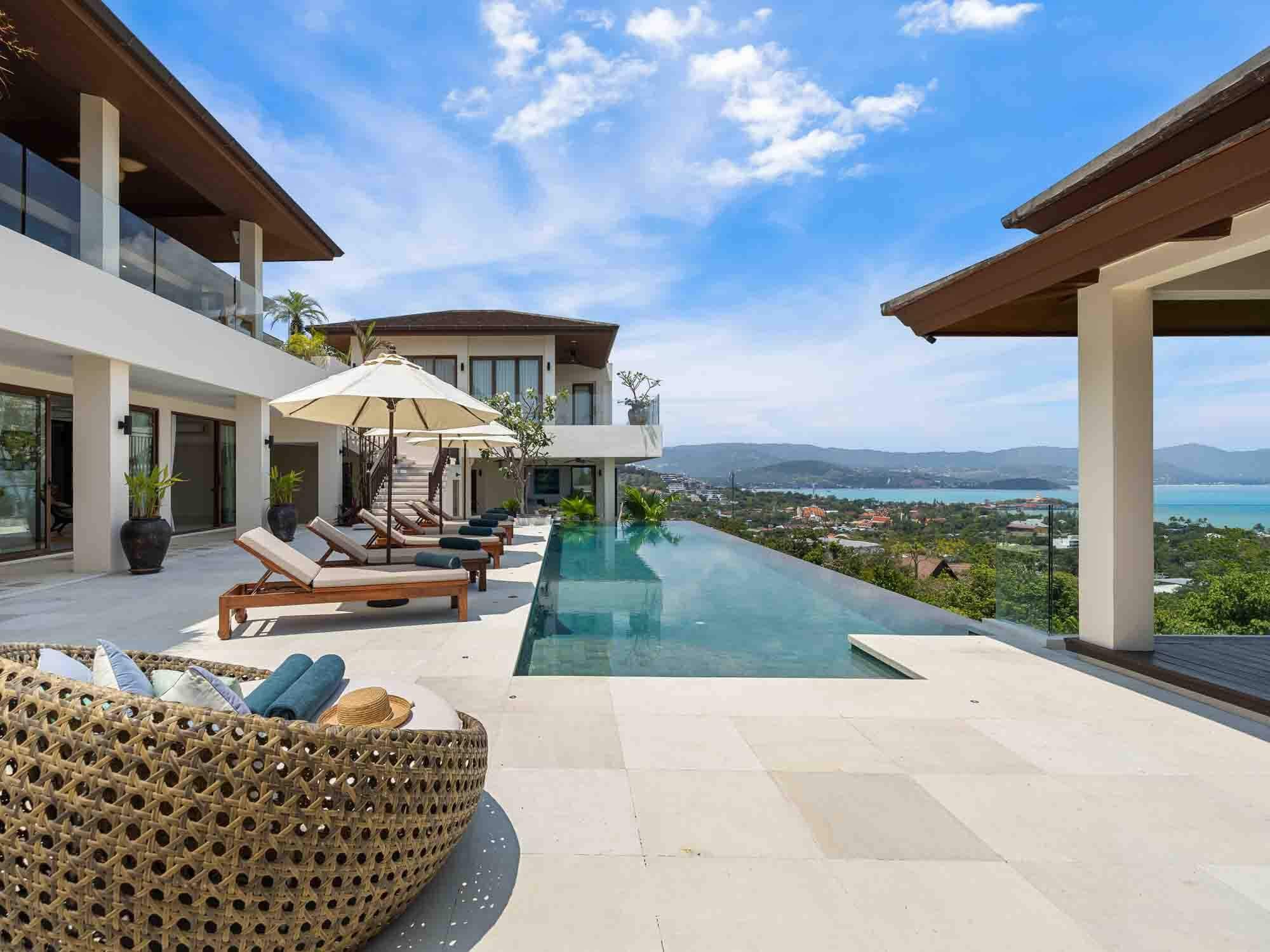 Wide view of Saensook eco villa's pool deck, infinity pool, and outdoor lounging area overlooking the coastal landscape of Koh Samui