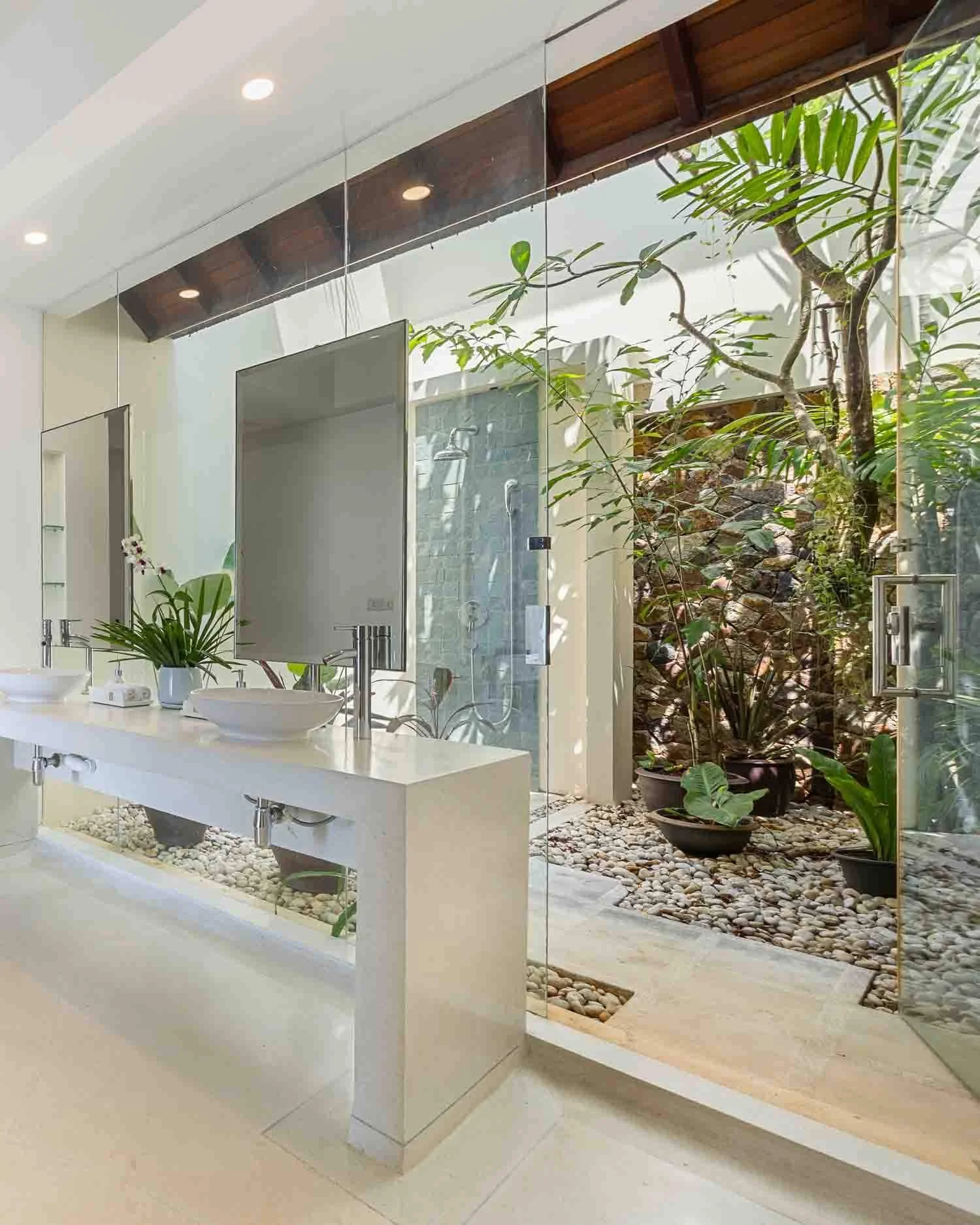 Modern en-suite bathroom vanity with dual vessel sinks, glass walls, and a lush private outdoor courtyard garden at Saensook villa