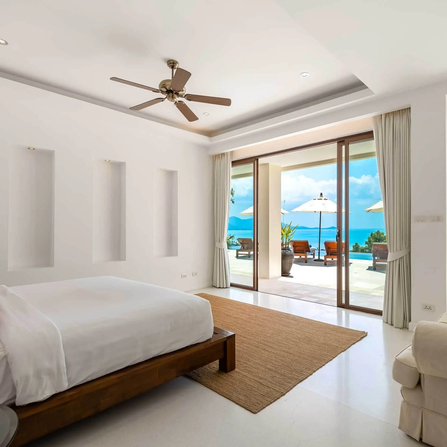 Spacious king bedroom suite featuring a ceiling fan and wide glass doors opening to a scenic balcony at Saensook eco villa
