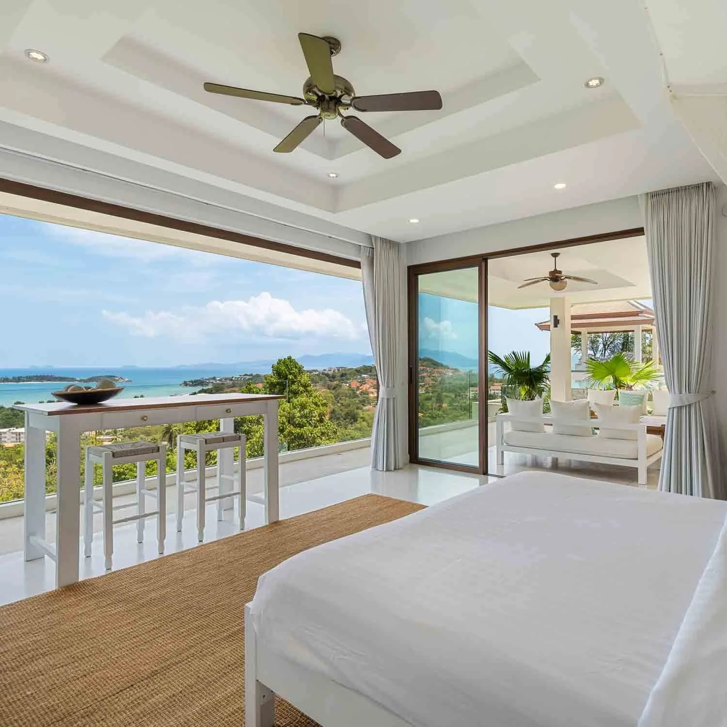 King bed suite with minimalist white decor and sliding doors leading directly to the pool deck and ocean views at Saensook eco villa Koh Samui