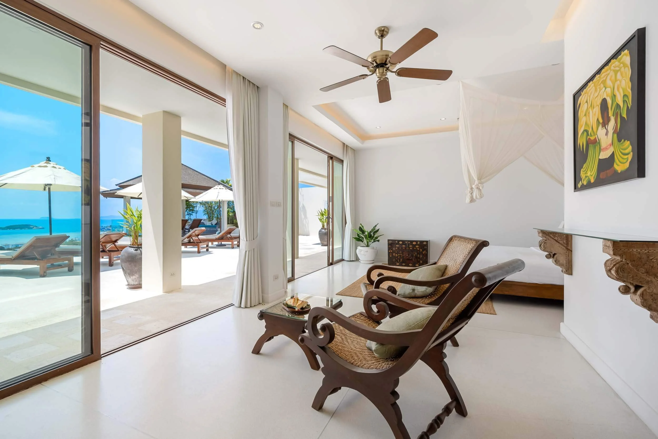 Spacious interior seating area with traditional wooden armchairs inside the Spa Suite, with sliding doors opening out to the pool terrace at Saensook villa