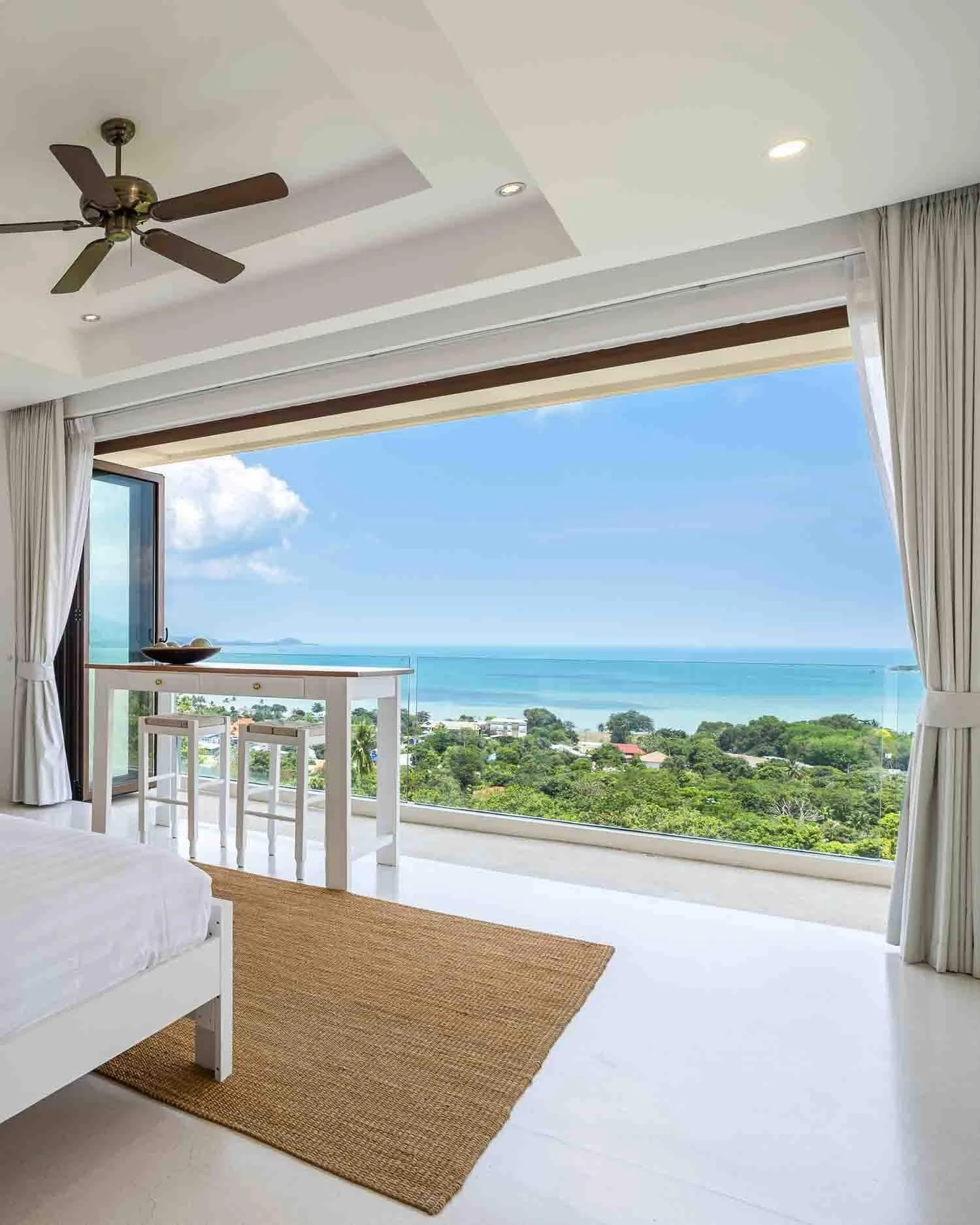 Bright bedroom suite interior at Saensook eco villa Koh Samui with expansive floor-to-ceiling glass doors opening to panoramic ocean views