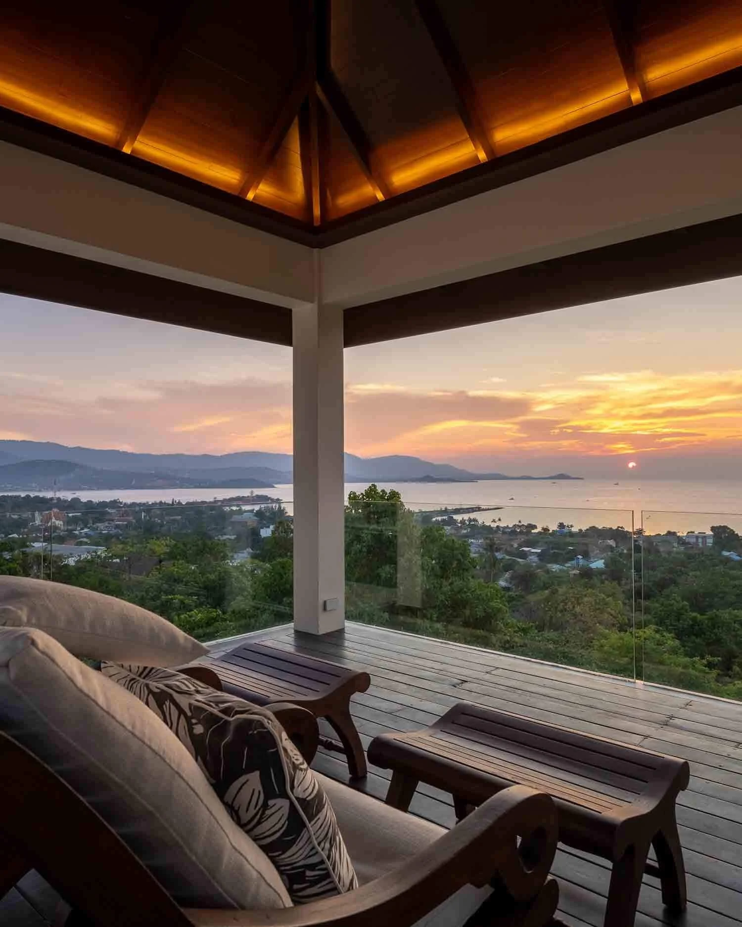 Breathtaking sunset view from a covered wooden balcony looking out toward the coastline and hills near Choeng Mon Beach at Saensook eco villa