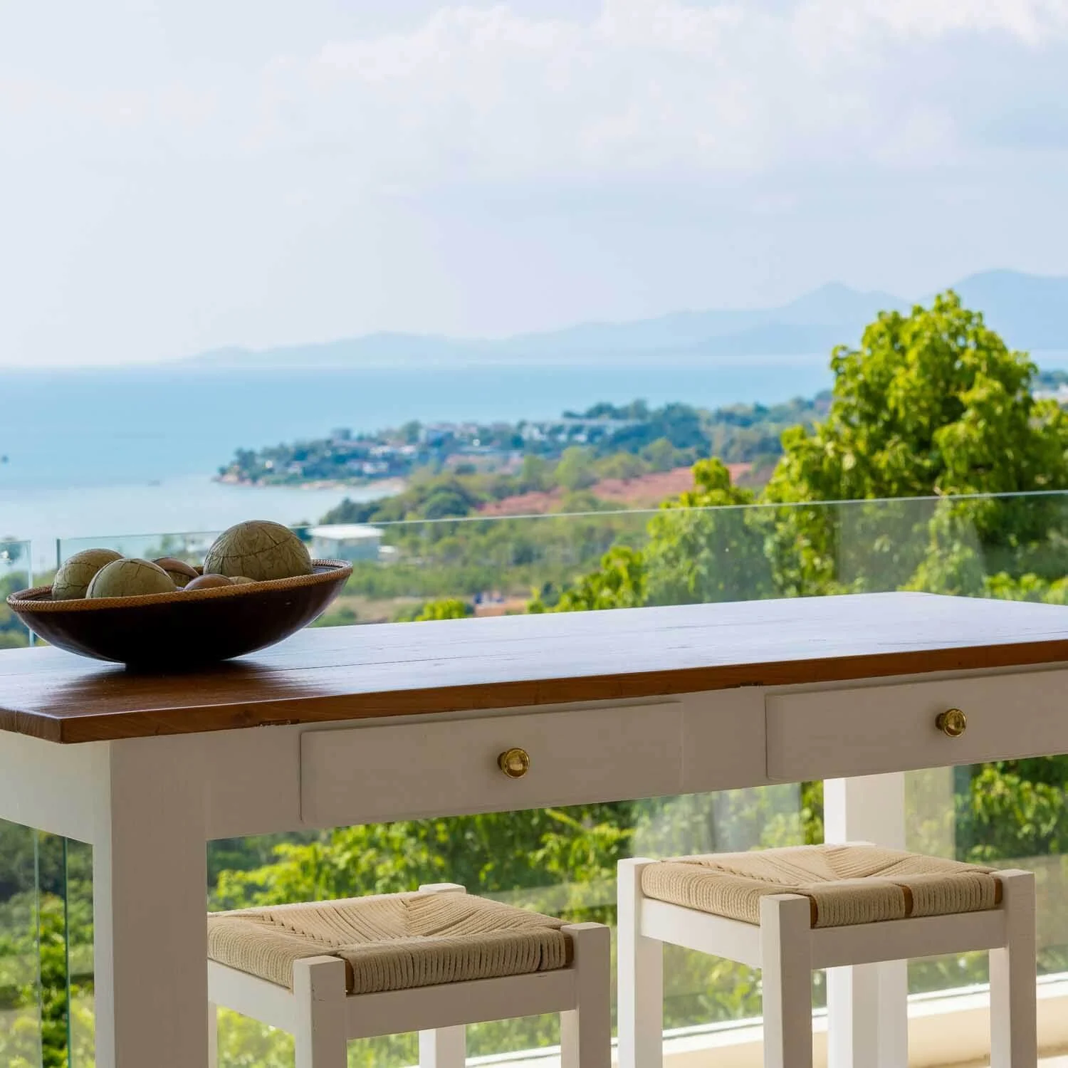 Close-up of a wooden vanity table with decorative bowl, overlooking the tropical coastline and sea near Choeng Mon Beach from Saensook villa