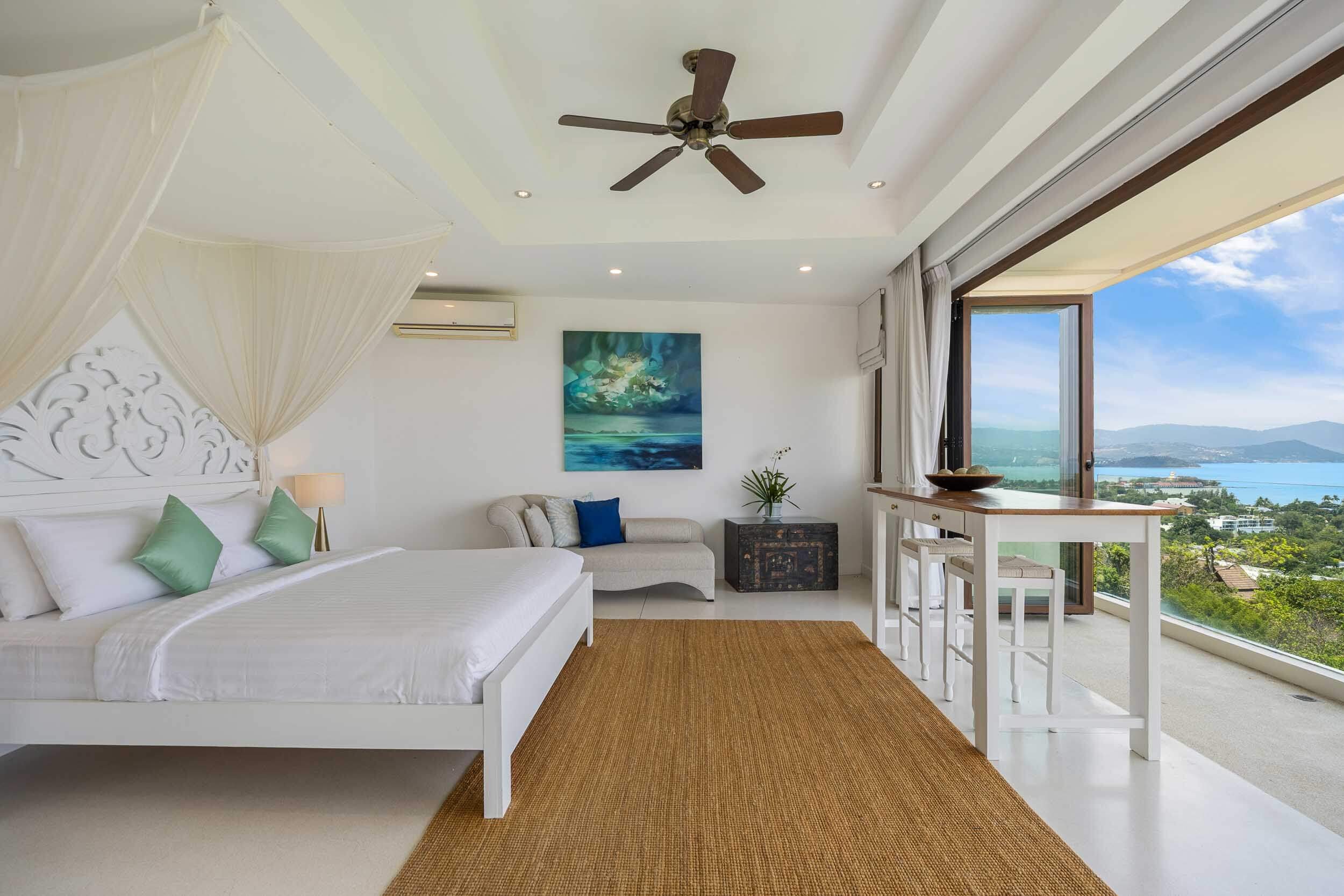 Daytime view of the bright Sundown Suite bedroom featuring a king bed, canopy, and sliding glass doors opening to panoramic sea views at Saensook eco villa