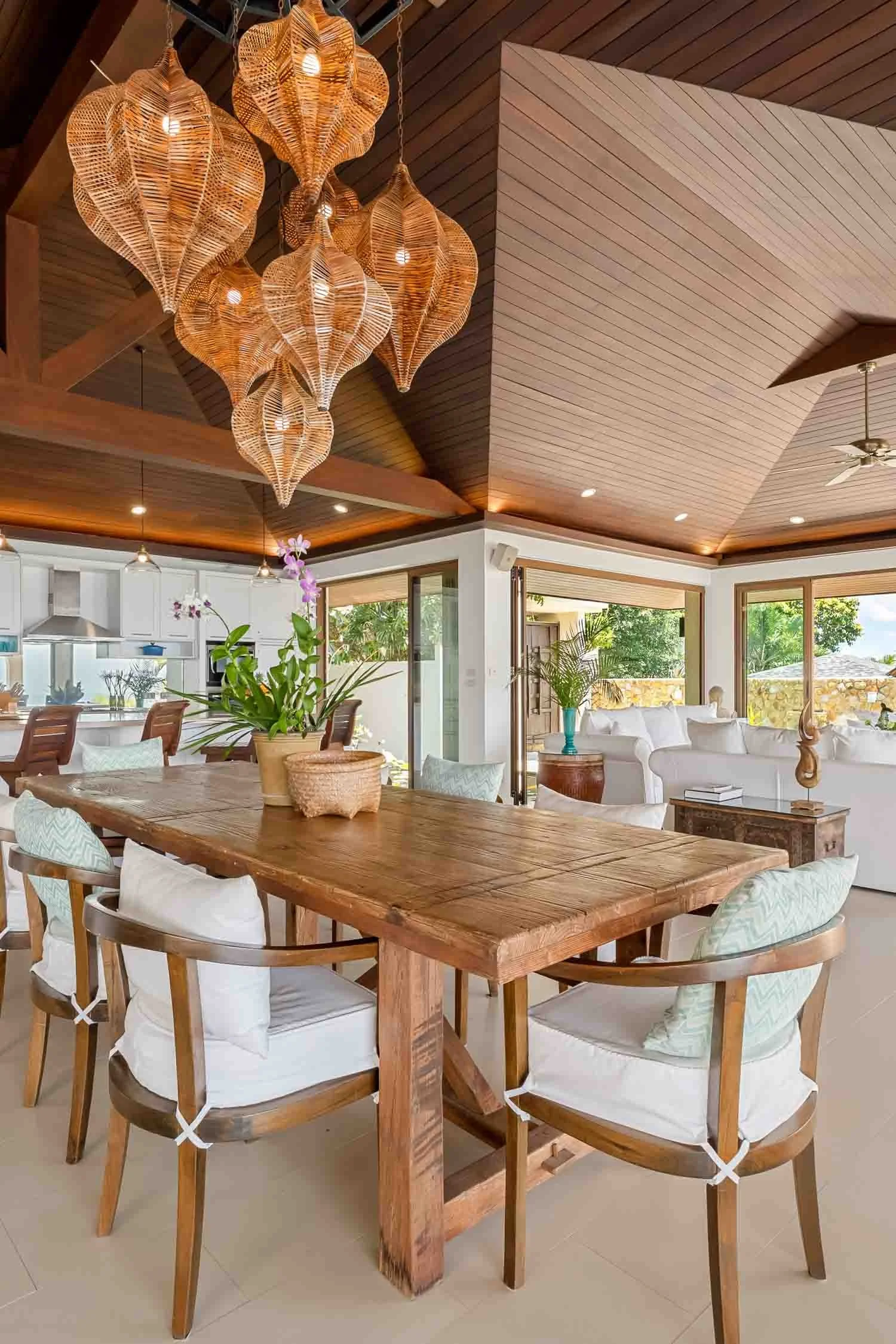 Elegant rustic wooden dining table surrounded by matching chairs beneath a cluster of woven pendant lights at Saensook eco villa