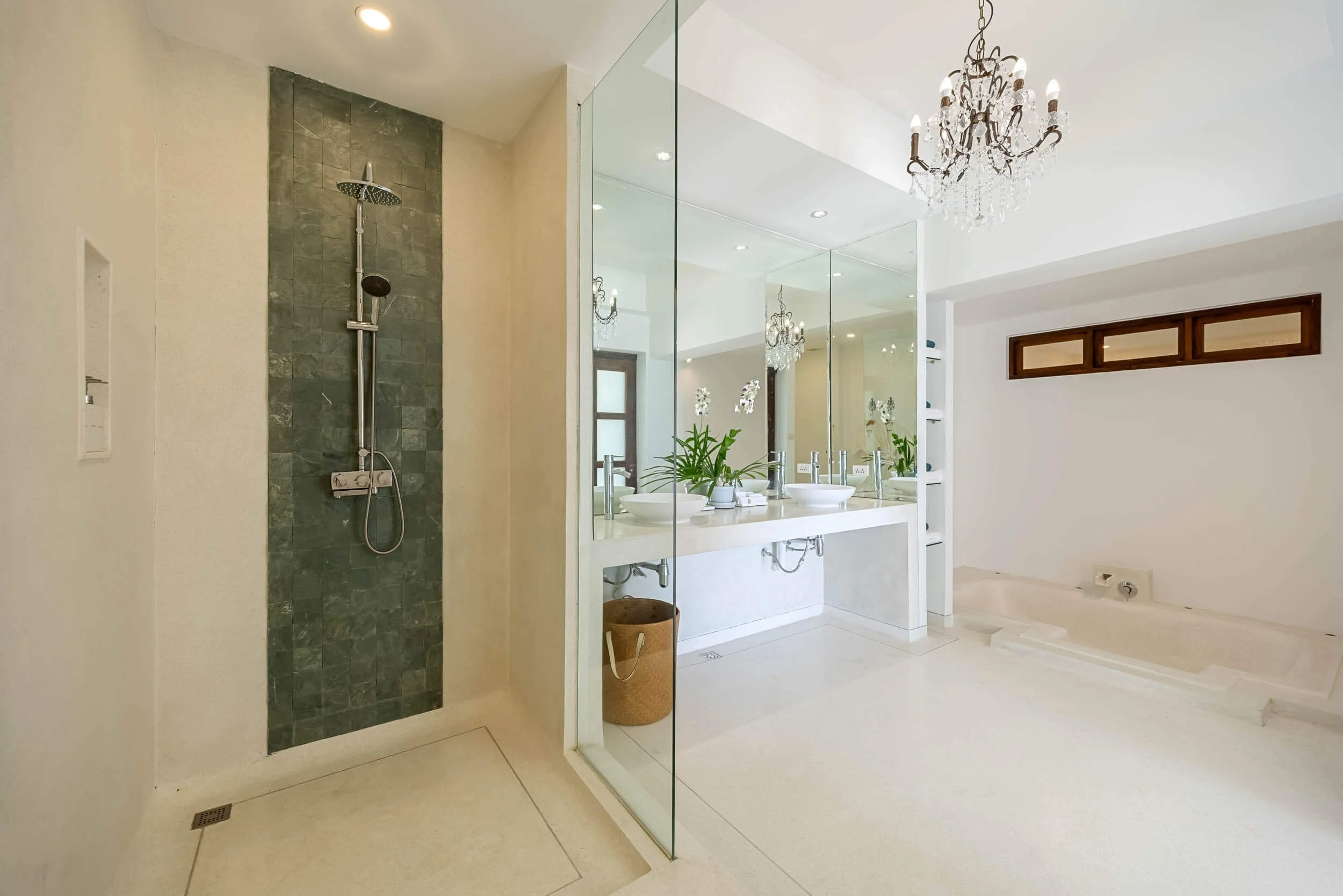 Luxury en-suite bathroom in the Spa Suite featuring a crystal chandelier, glass-walled walk-in slate shower, dual vessel sink vanity, and deep soaking tub at Saensook eco villa