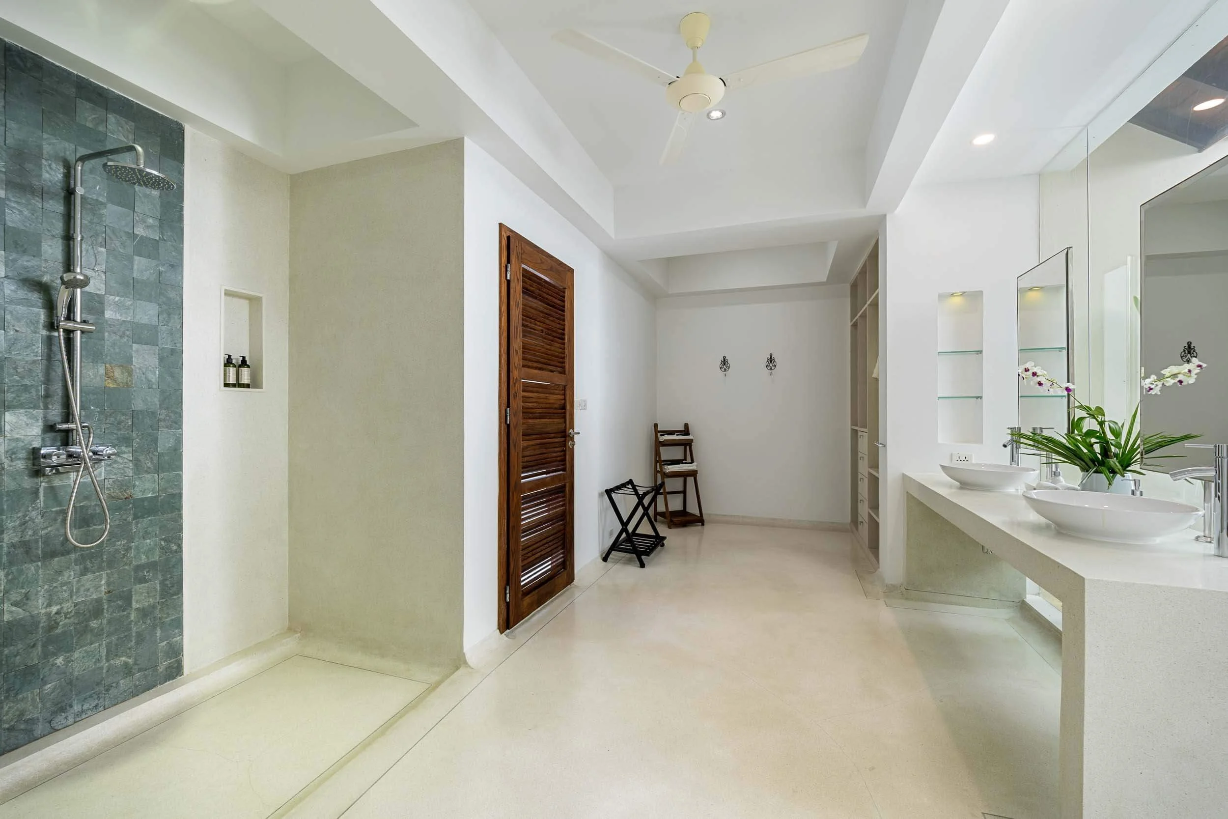 Spacious en-suite bathroom of the Sundown Suite showing a walk-in slate stone shower, dual vessel sinks, and wooden louvered doors at Saensook villa