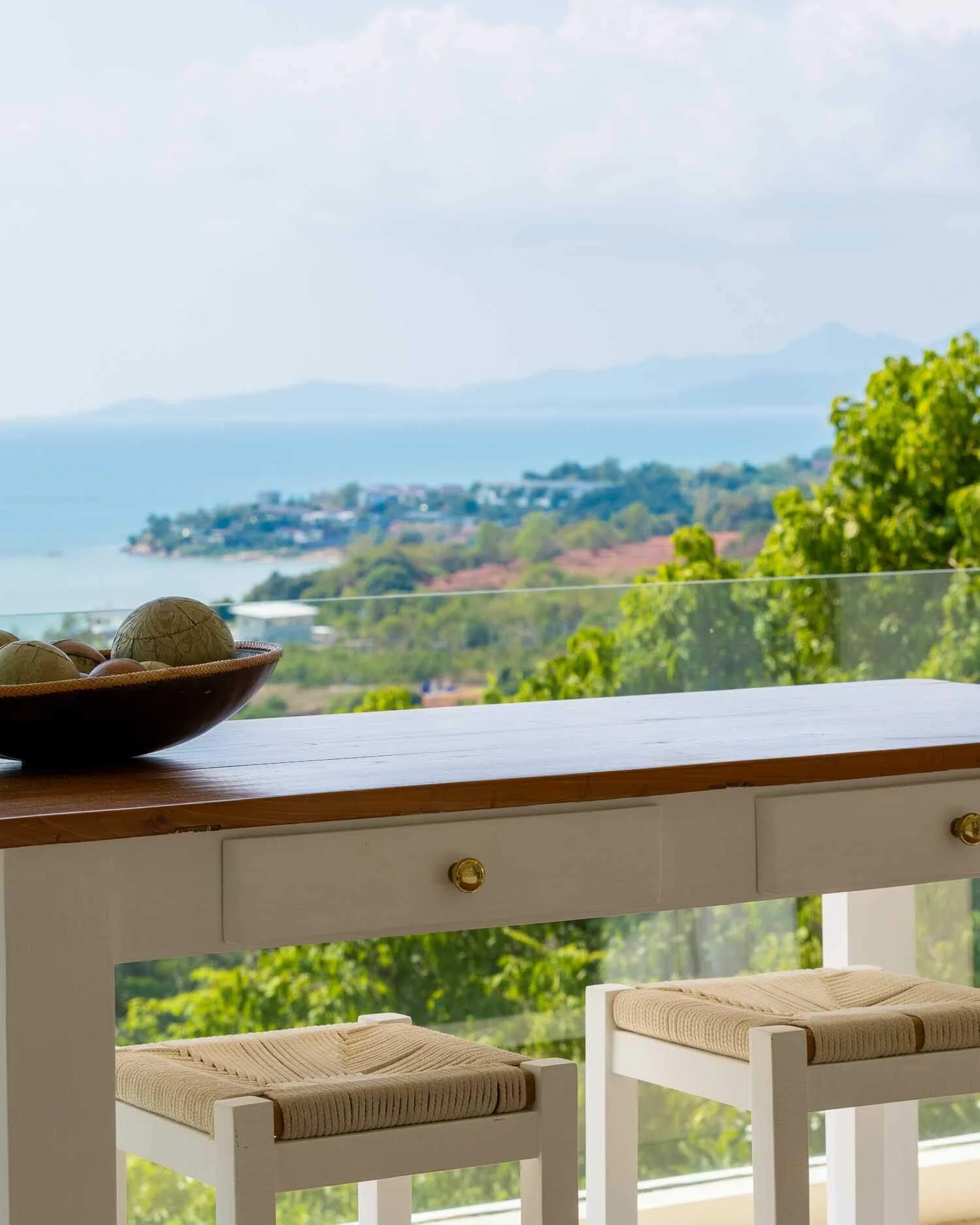 Wooden table with a decorative bowl overlooking the coastal landscape and sea from the Sundown Suite balcony at Saensook villa