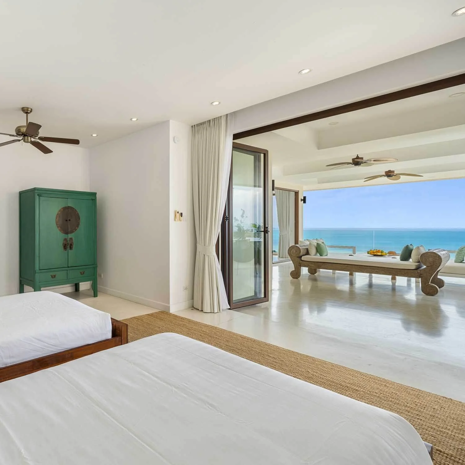 Twin bedroom layout with a vibrant green traditional cabinet, opening out to a furnished sea-view terrace at Saensook villa
