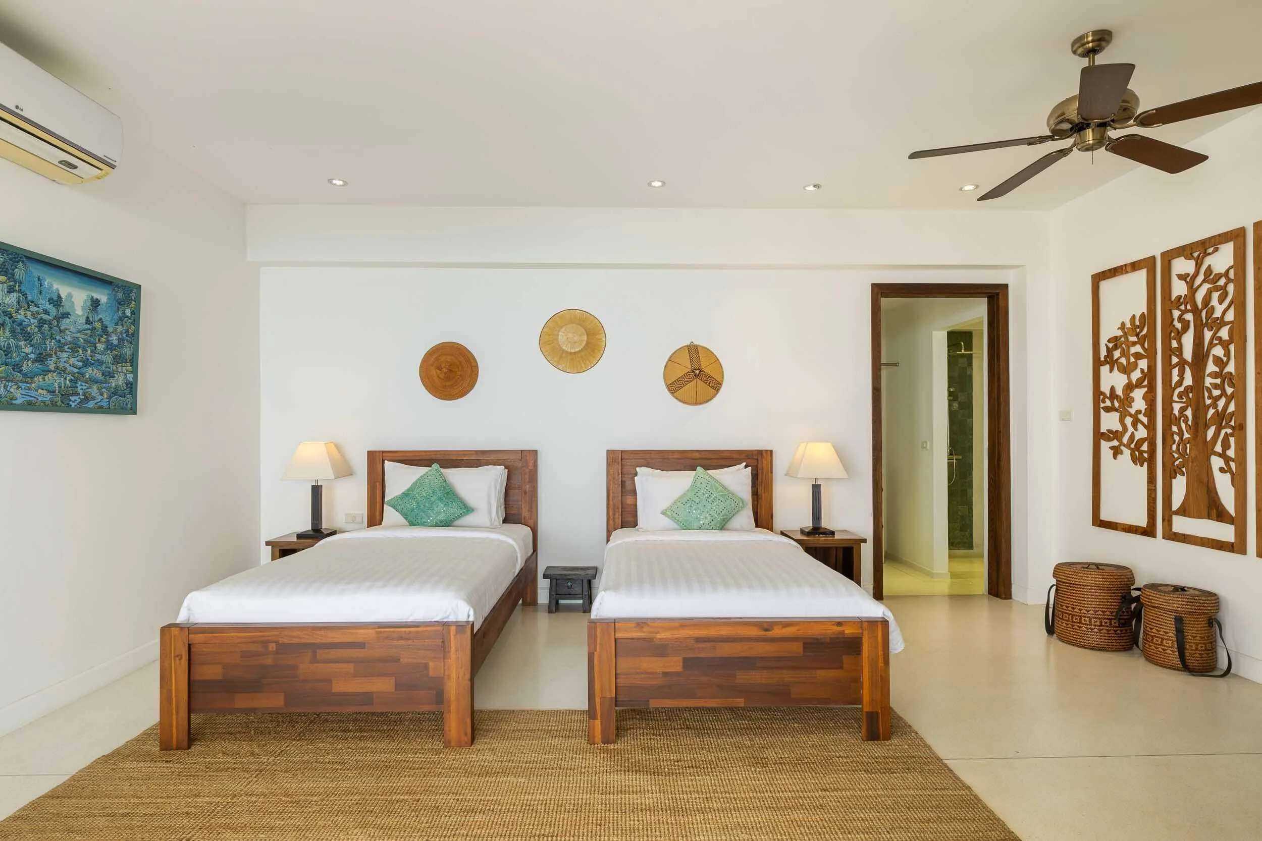 Twin bedroom layout featuring wooden frames, crisp white linens, teal accent cushions, and traditional Thai decor at Saensook villa