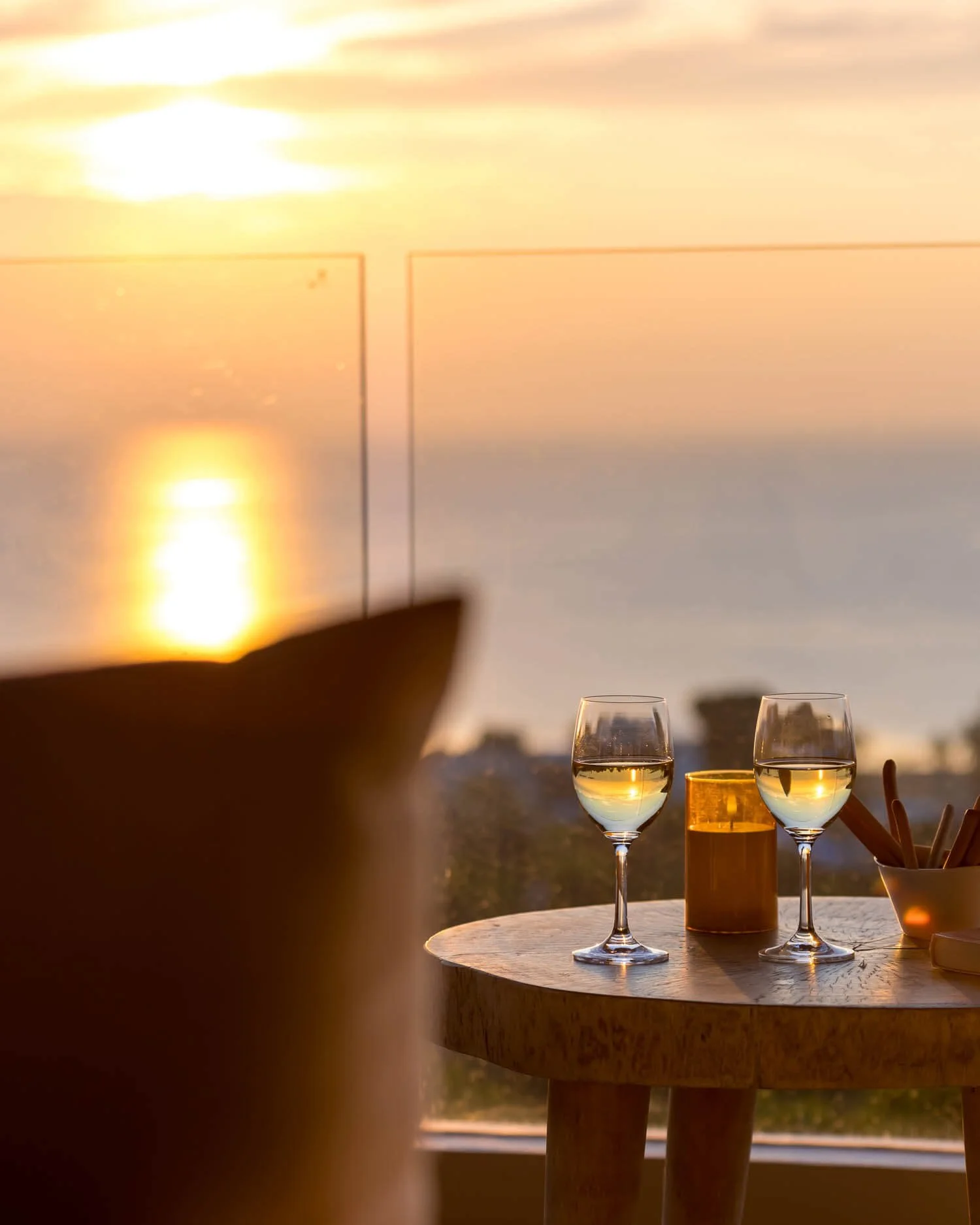 Two glasses of wine on a table during a golden sunset, overlooking the sea from the private balcony at Saensook eco villa
