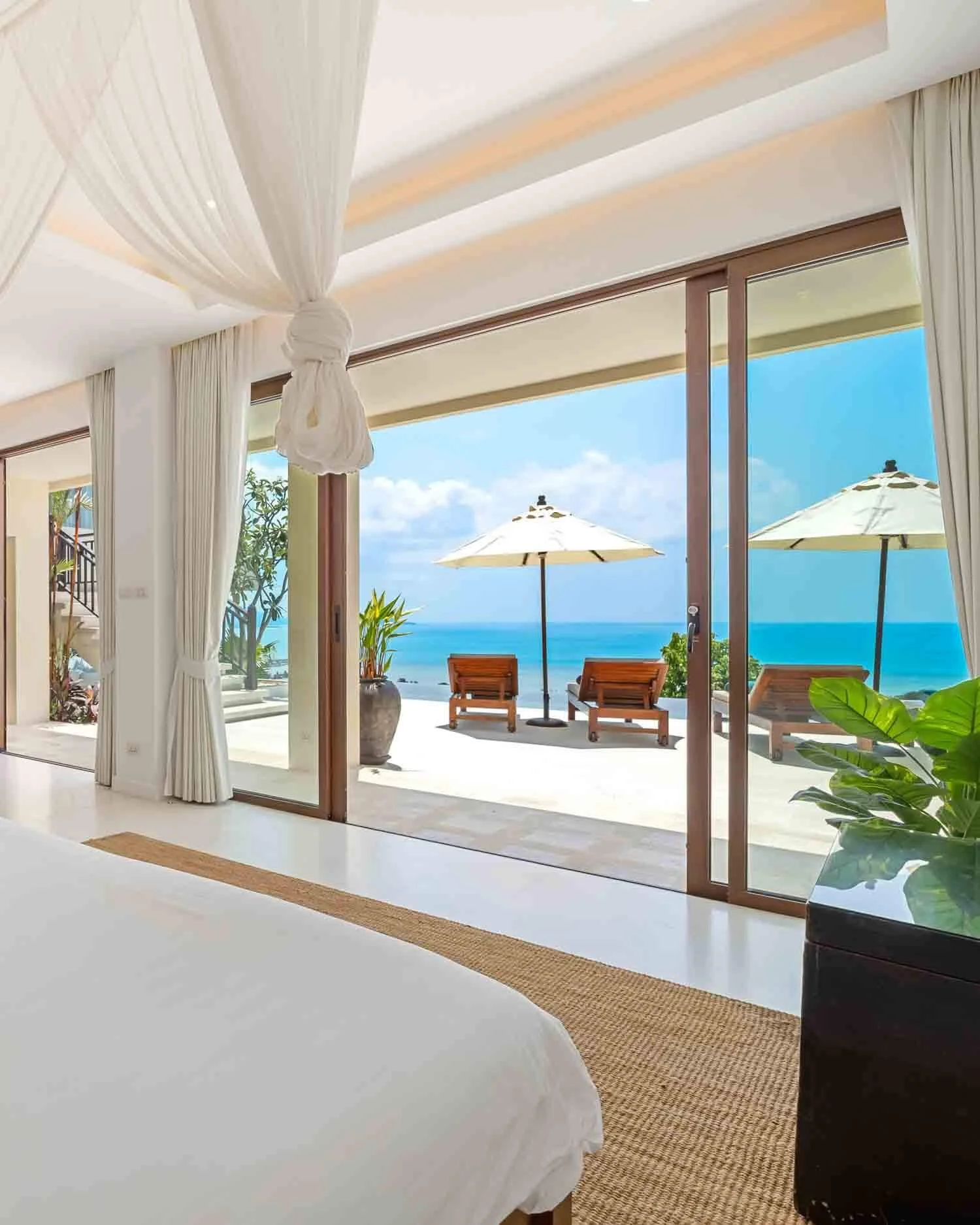 Spacious bedroom suite featuring a draped canopy bed and sliding glass doors leading to the sun deck at Saensook eco villa