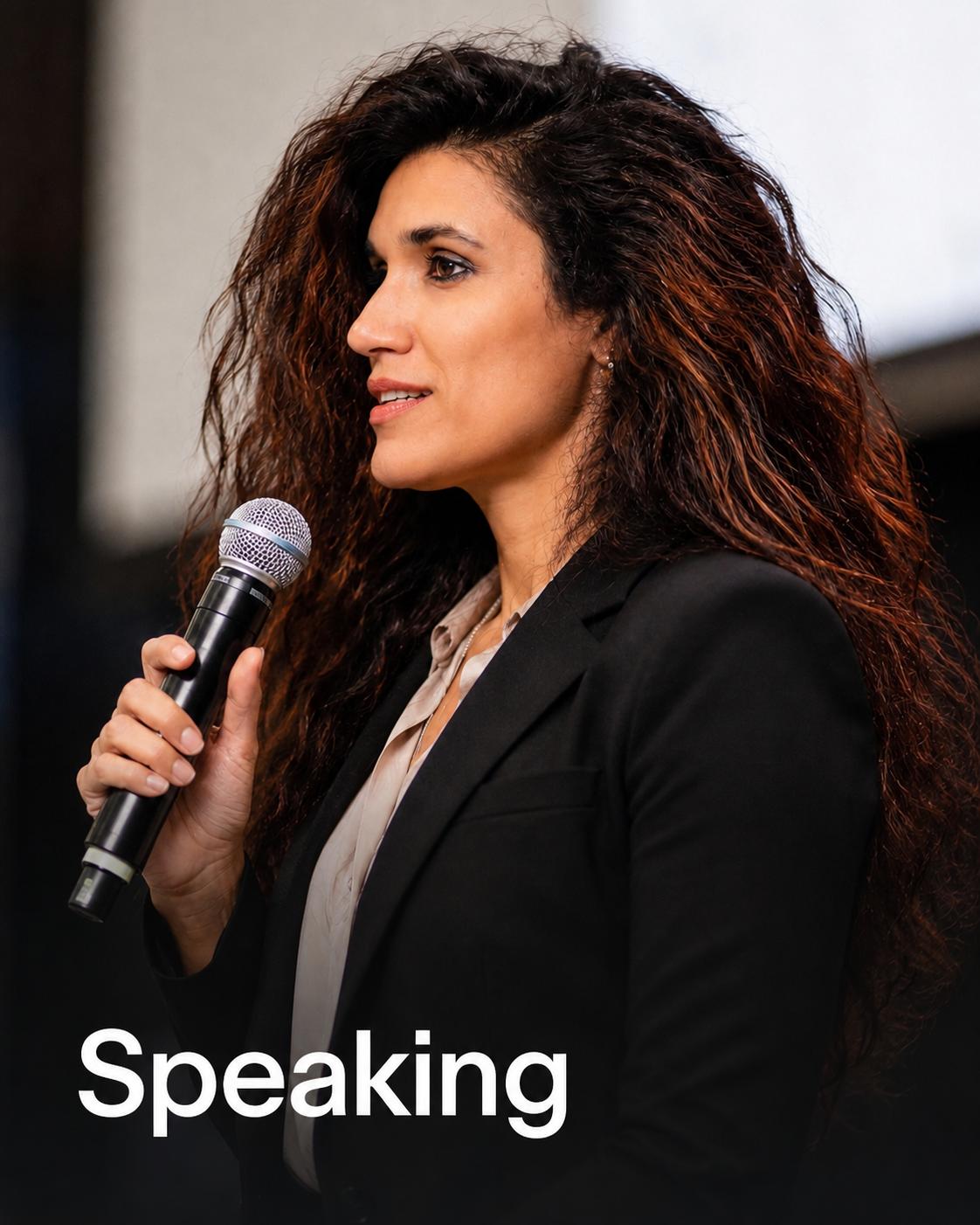 Abbie Pratt speaking to an executive audience with a microphone.