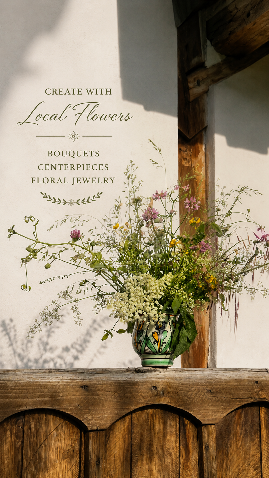 A decorative wall sign reads 'Create with Local Flowers, Bouquets, Centerpieces, Floral Jewelry' next to a colorful floral arrangement in a decorative vase on a rustic wooden surface.