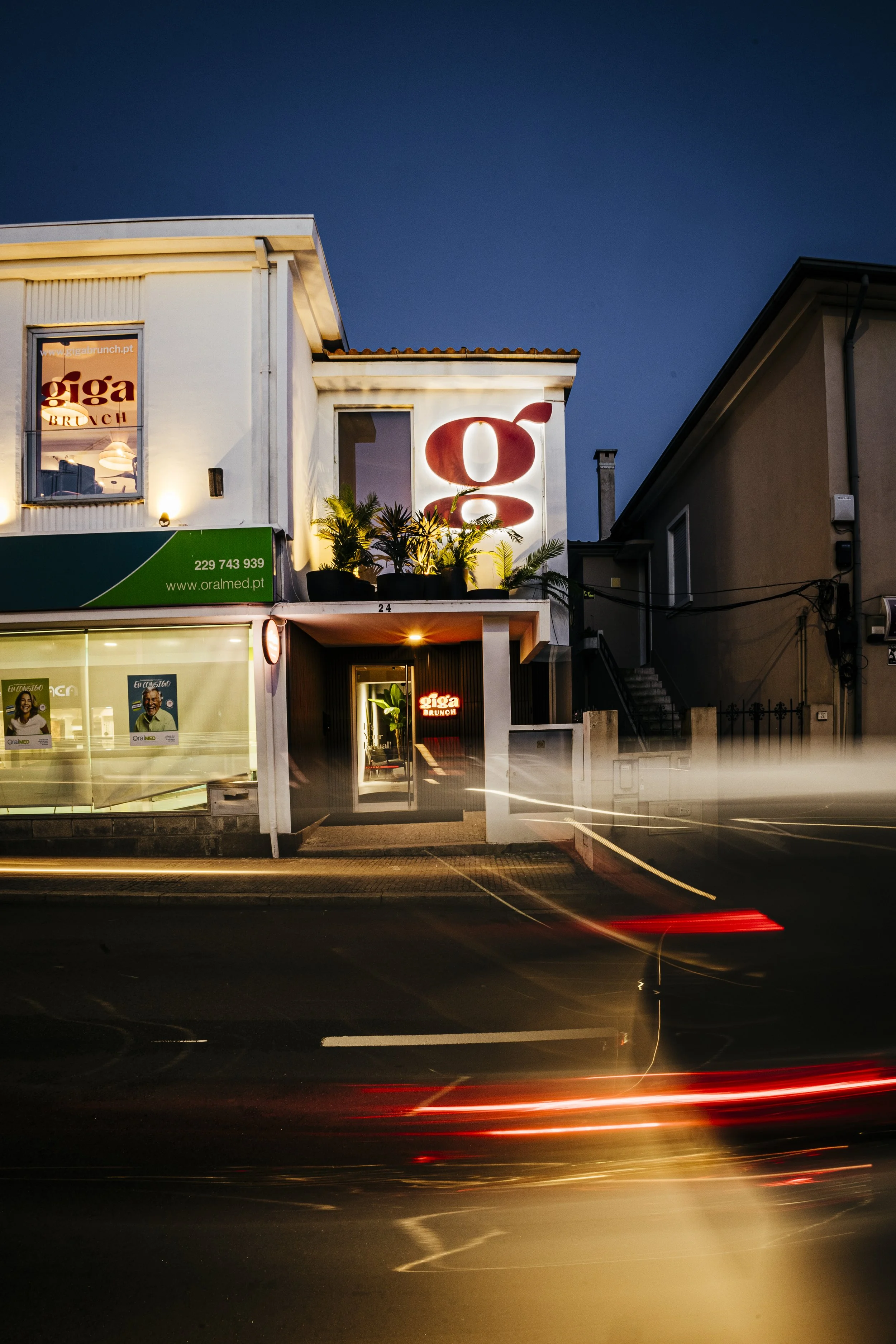 Fachada do Giga Brunch vista da rua à noite, com letreiro luminoso, perto do Porto