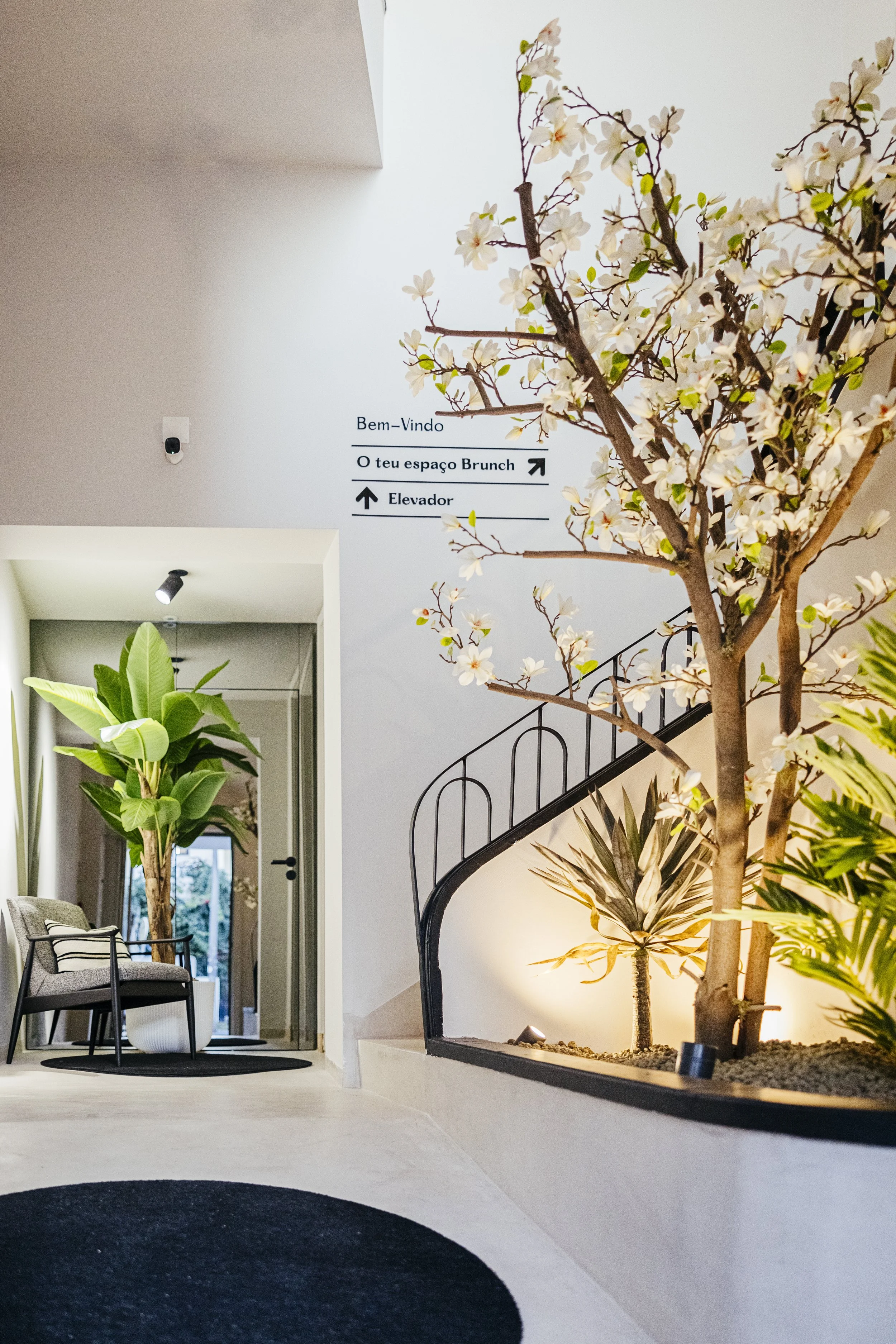 Interior do Giga Brunch junto às escadas da entrada, com plantas e decoração floral