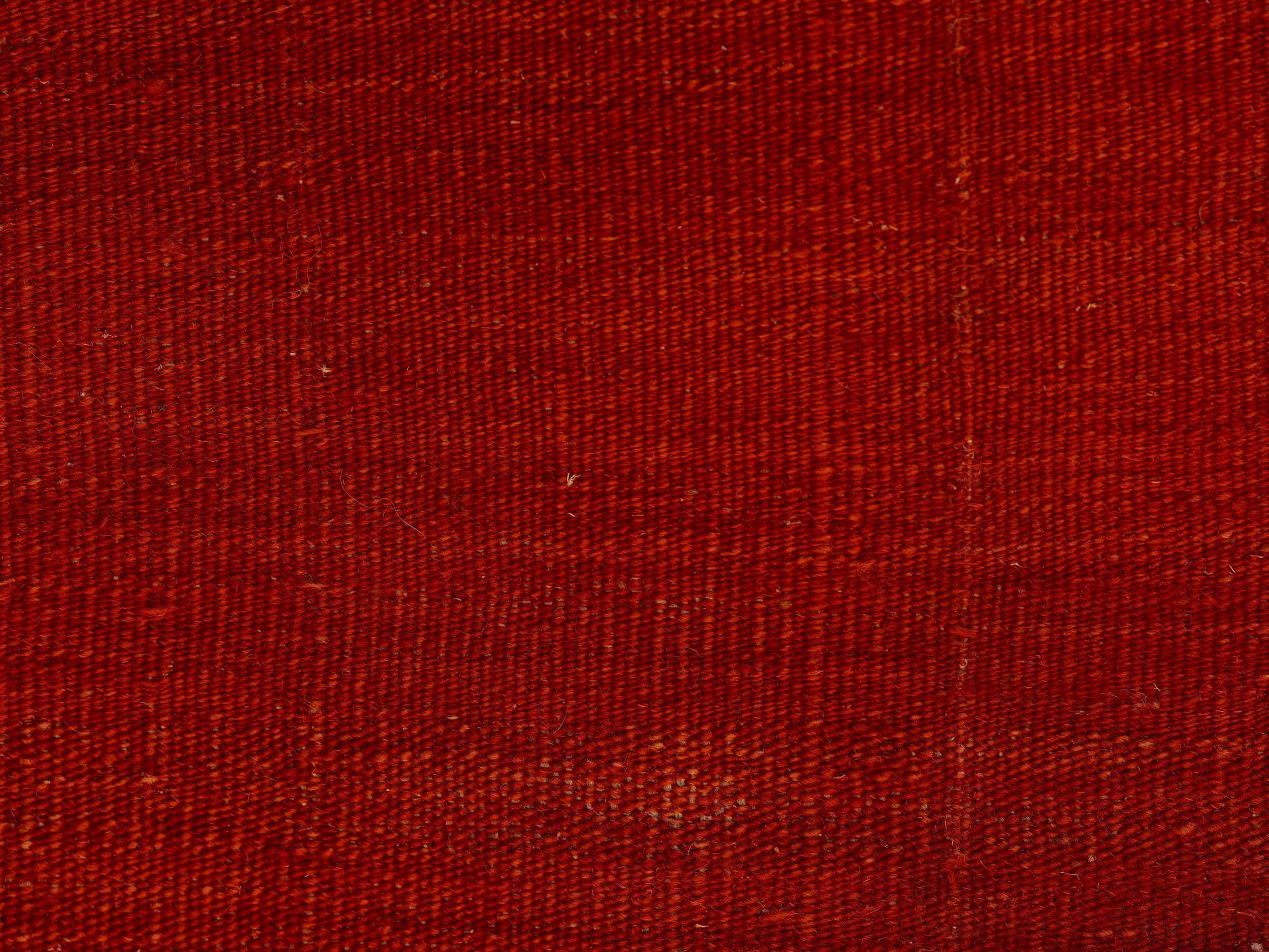Close-up of red textile fabric with visible woven texture and small fibers.