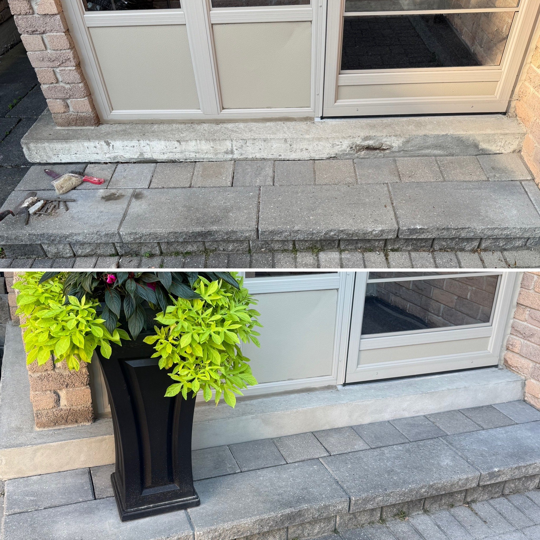 A black planter with a variety of green and pink flowering plants standing on a grey paved surface outside a building with brick and beige siding, near a corner of a glass door or window.