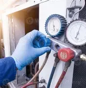 Technician wearing blue gloves adjusting pressure gauges on industrial equipment.