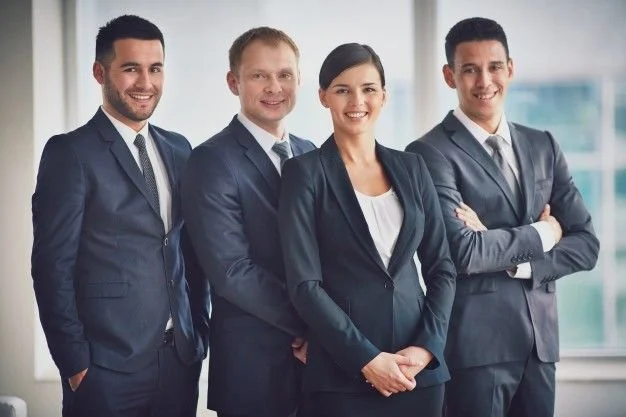 Four professionals in business suits standing together in an office.