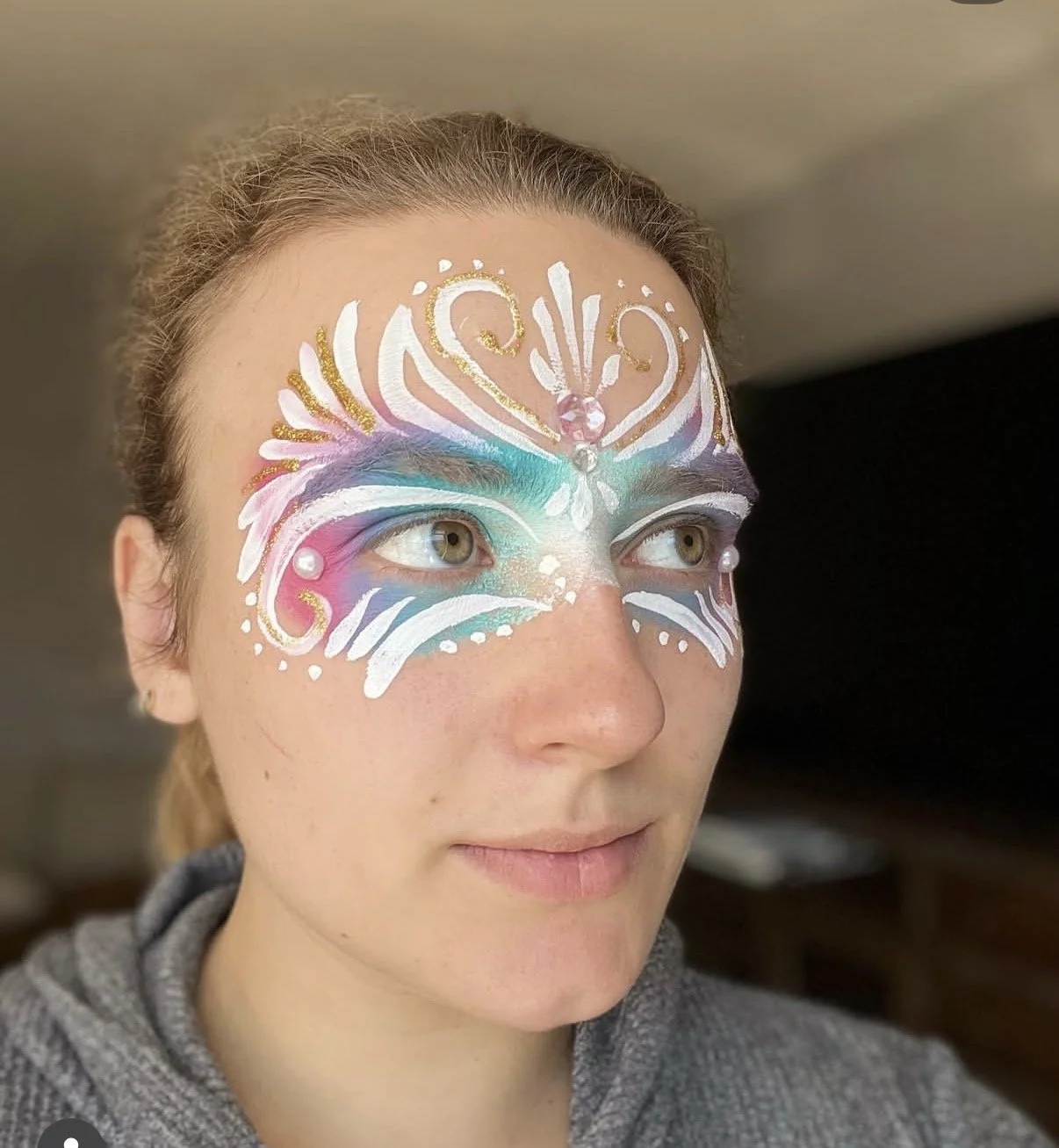 Pastel butterfly face painting design with blue, pink, white, and gold details.