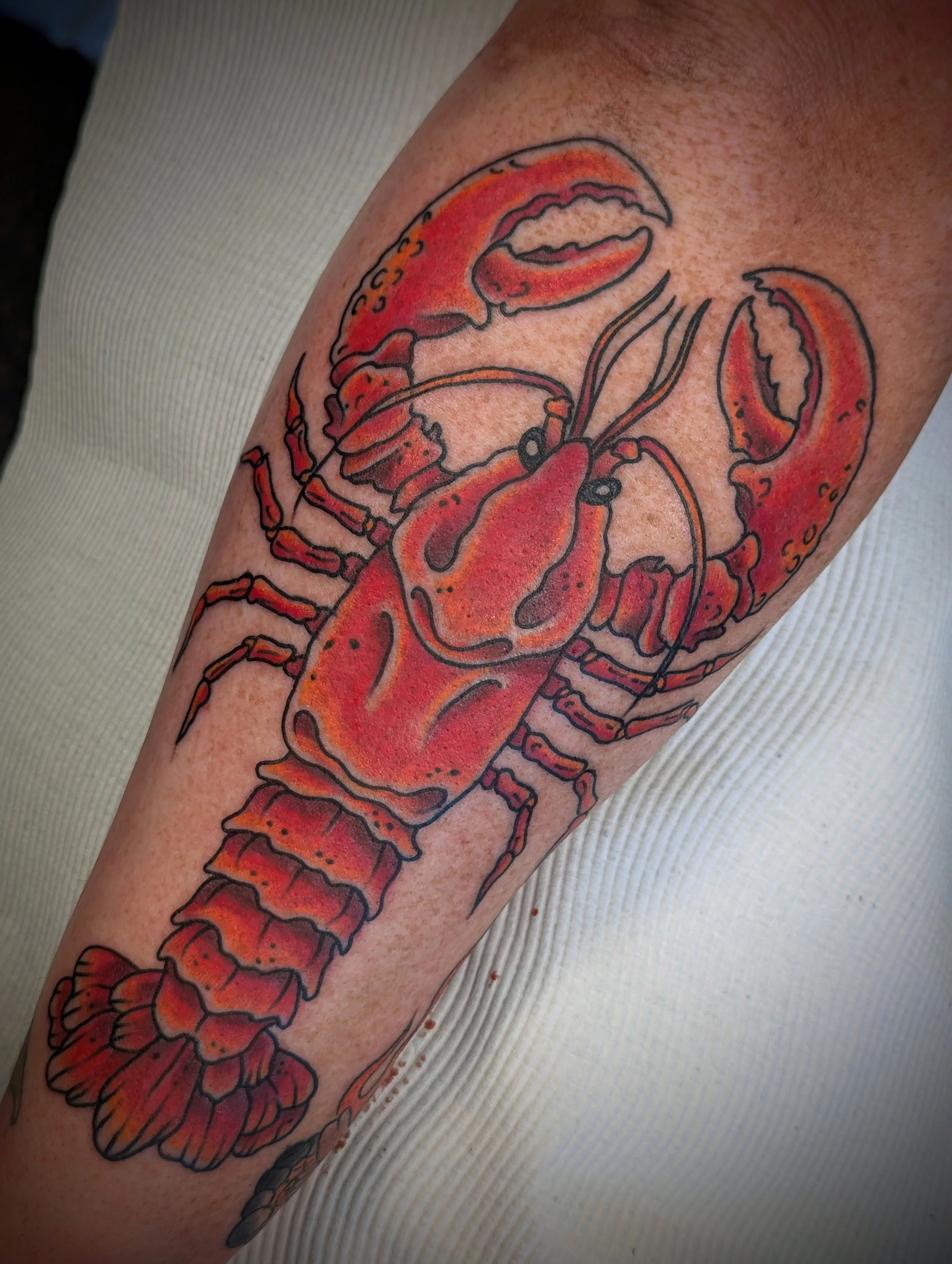 Tattoo of a red lobster on a person's arm.
