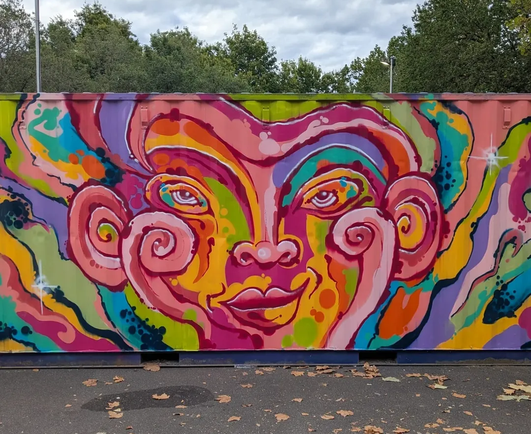 Colorful mural of a woman's face painted on a large wall, with swirling patterns and vibrant colors.
