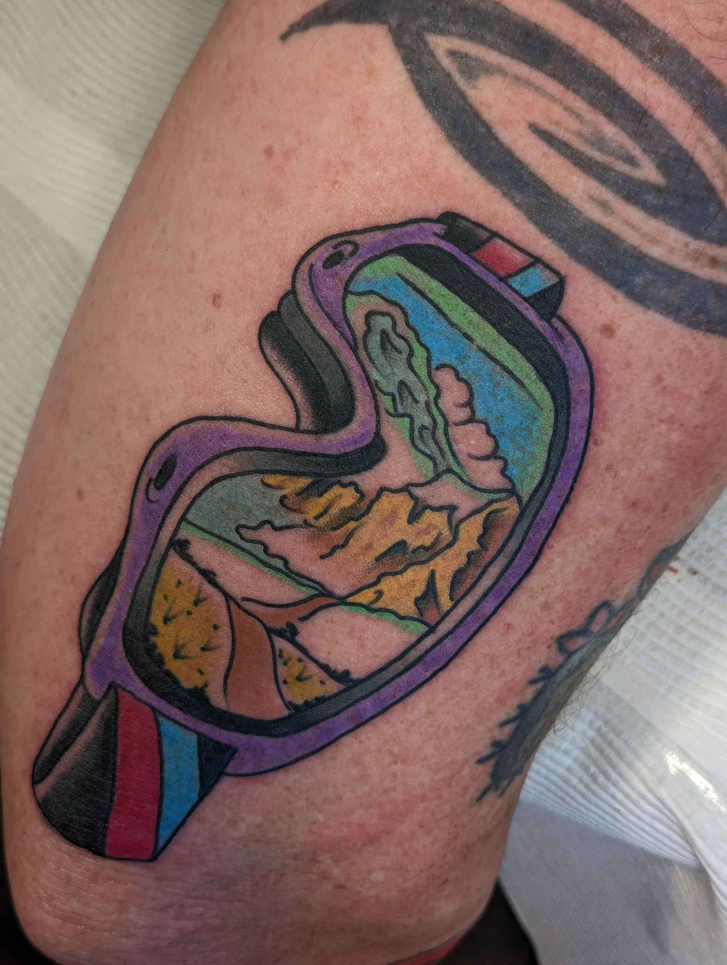 Close-up of a colorful tattoo of a rocket ship on a person's arm.