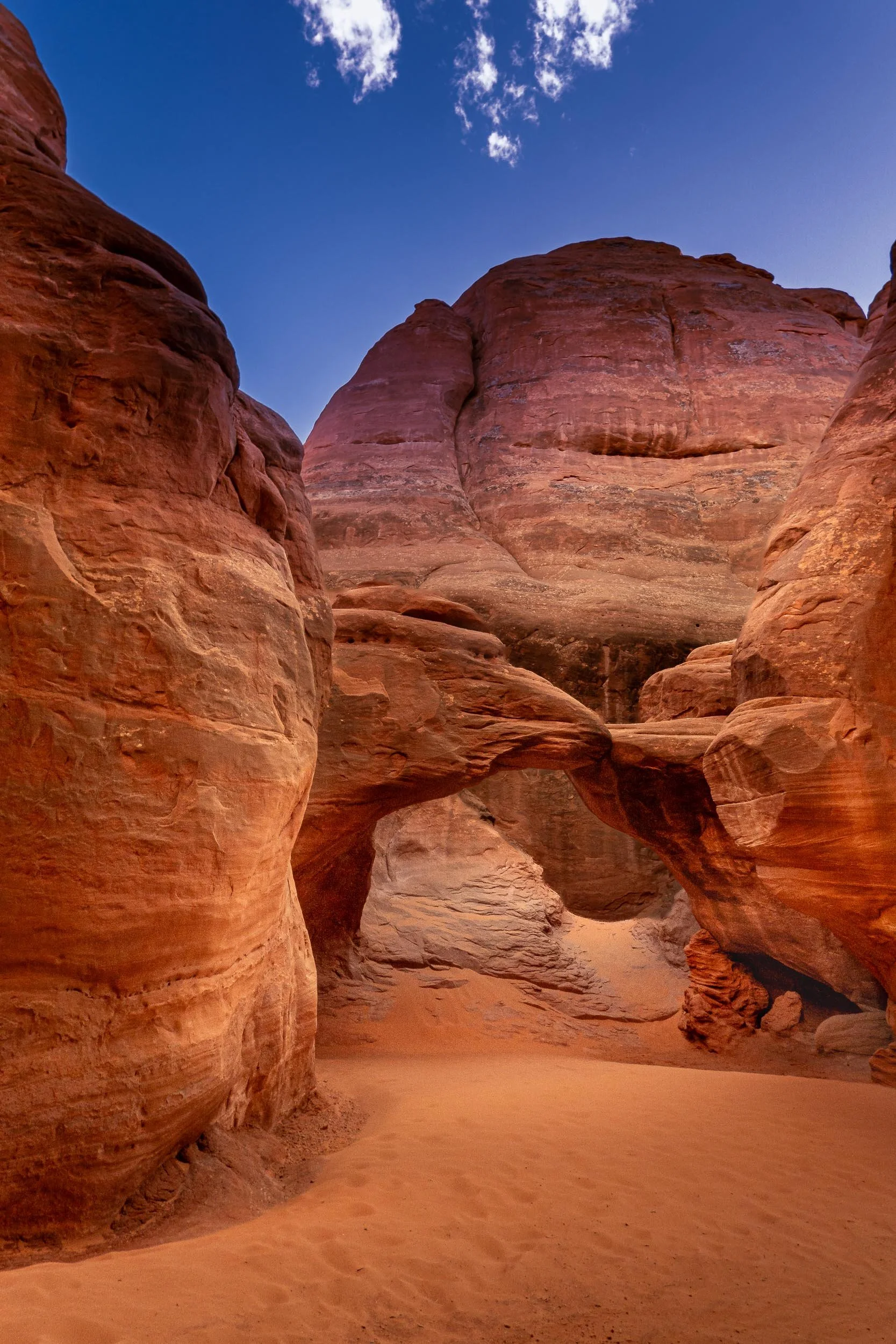  The Hidden Gateway 
Tucked away behind towering rock walls, this hidden sanctuary evokes a sudden, breathtaking sense of discovery as the desert heat gives way to cool, quiet shade. Squeezing through a narrow sandstone slot reveals a soft, beach-lik